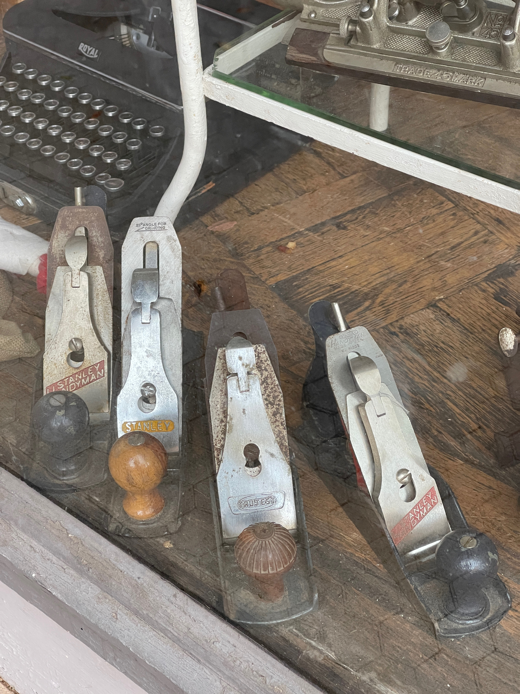 4 antique wood planes in a row in a shop window.