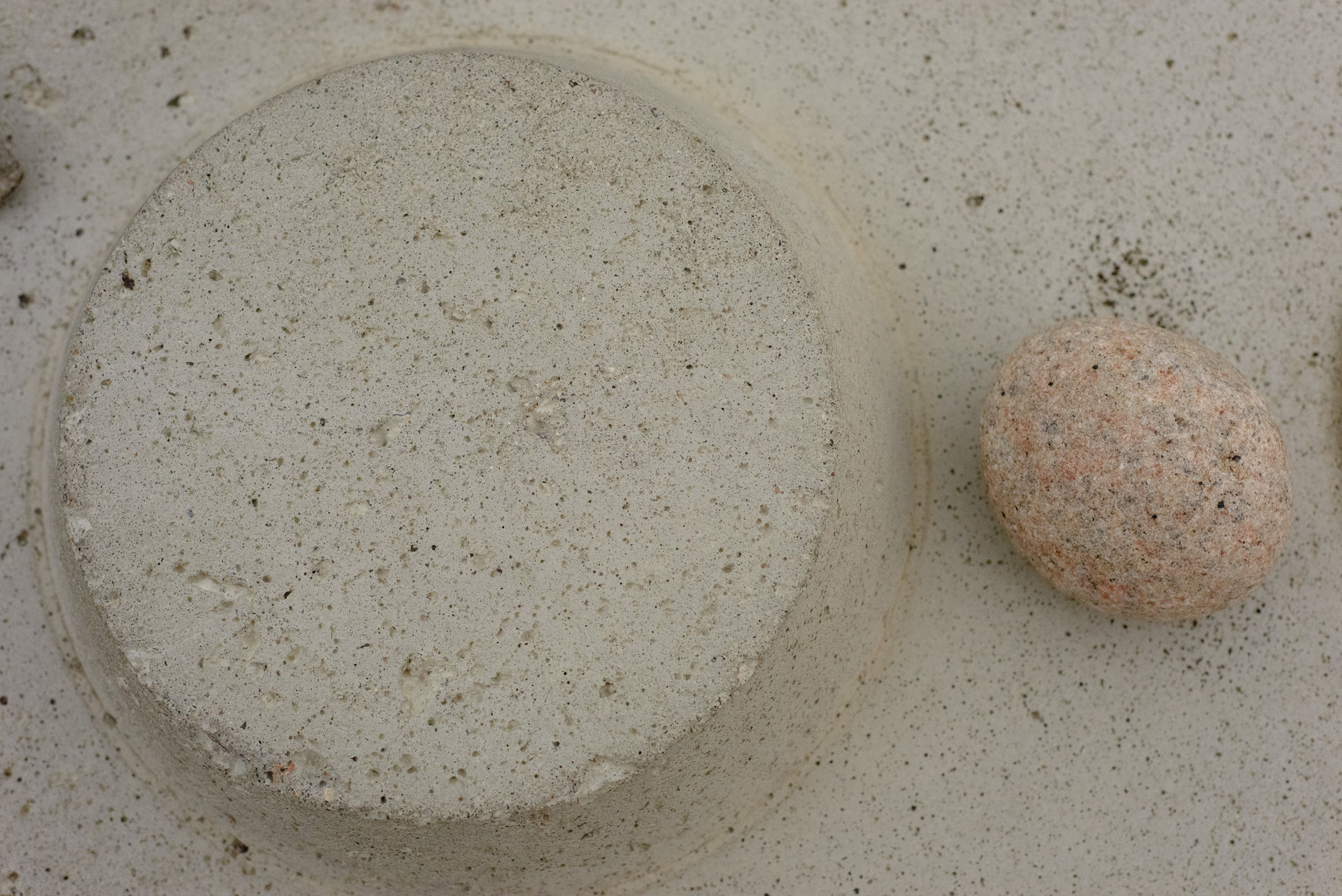 Raised concrete circle with matching color rounded rock beside.