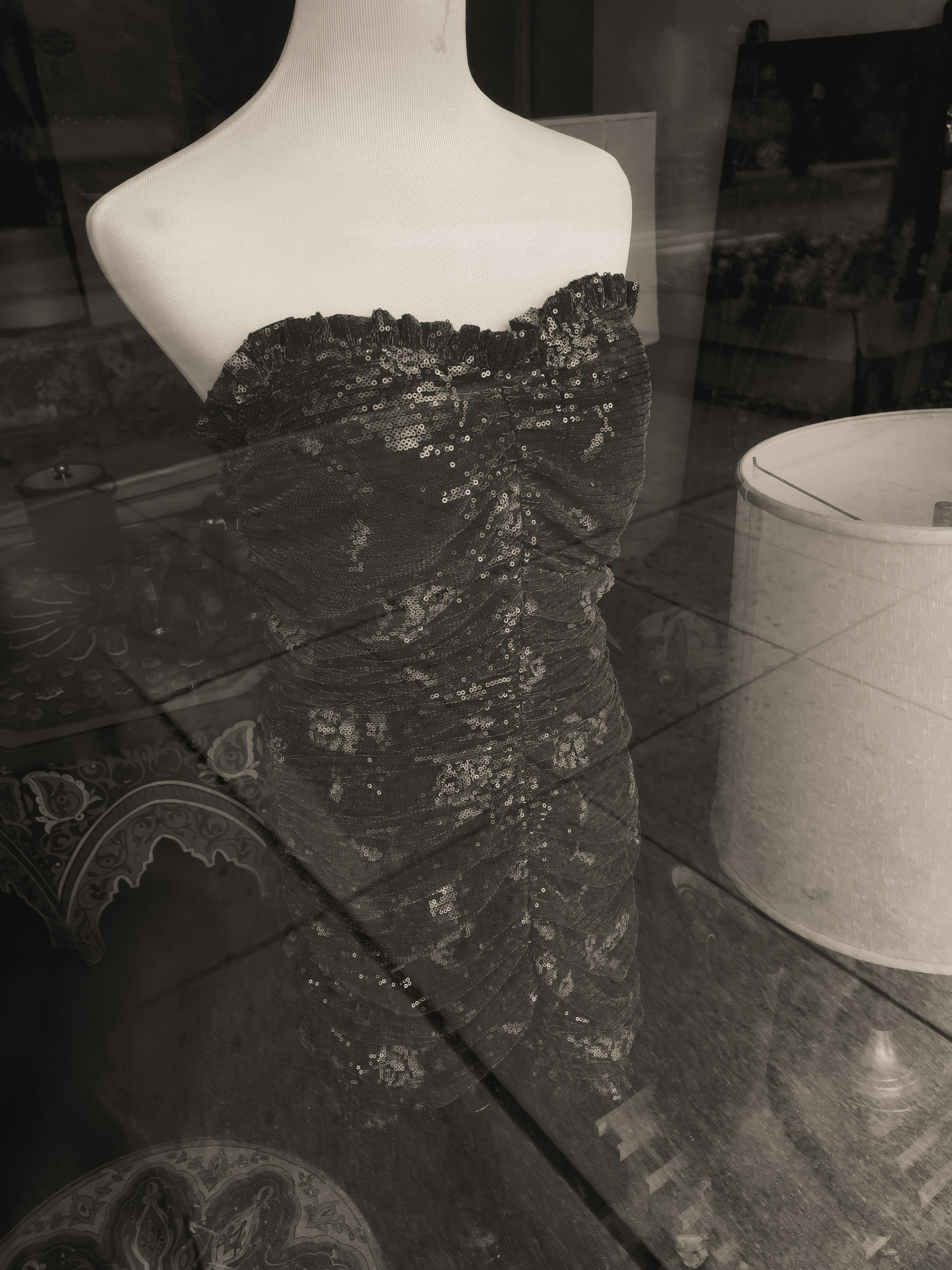 Dark gray strapless sequin dress on a mannequin in a shop window.