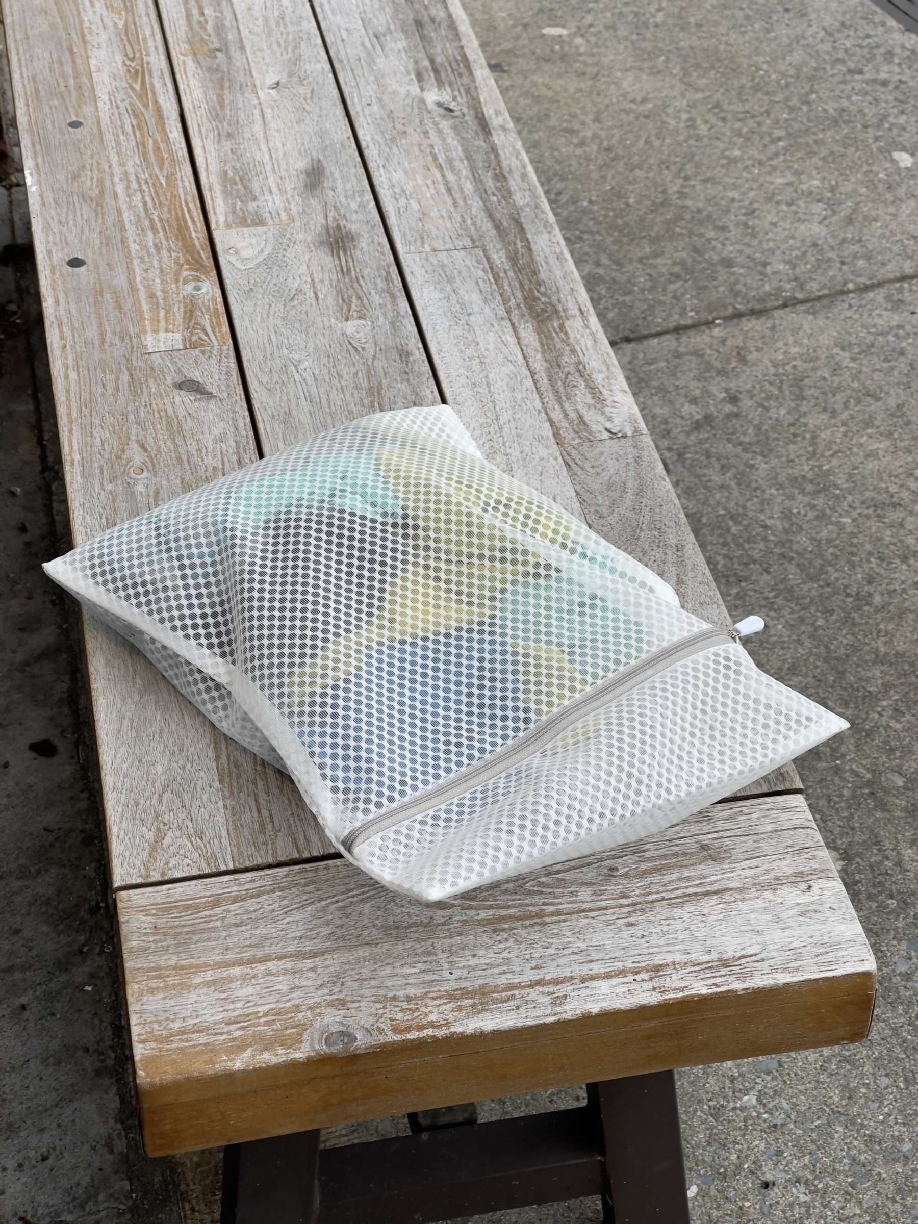Mesh pouch with colorful things inside left on a bench.