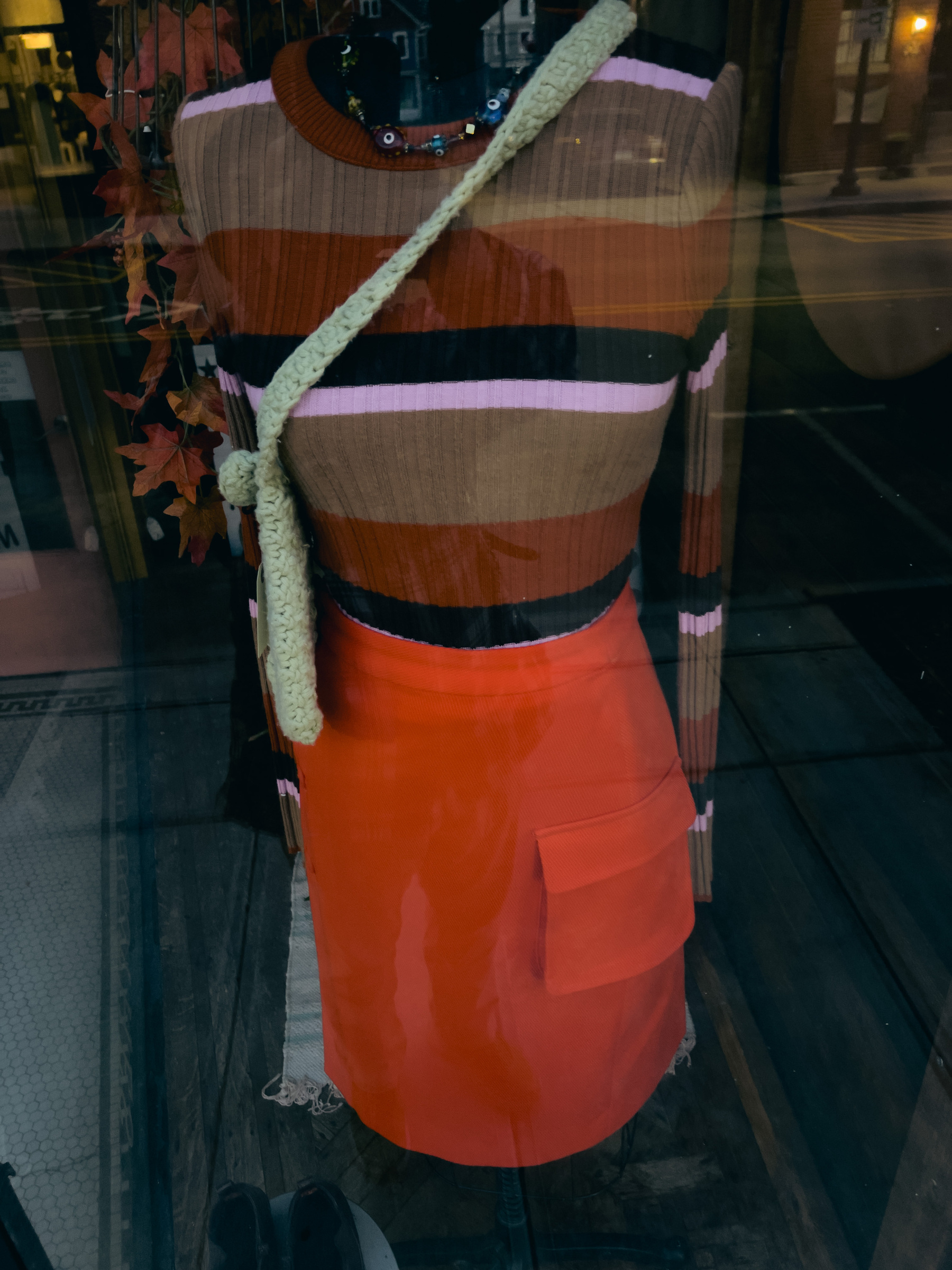 Red skirt and complimentary striped knit top on a mannequin in a shop window.