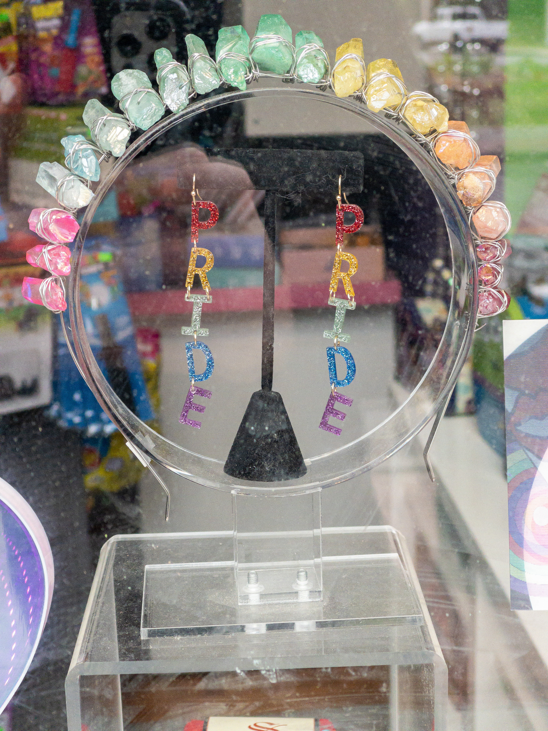 Pair of dangling pride earrings in a shop window.