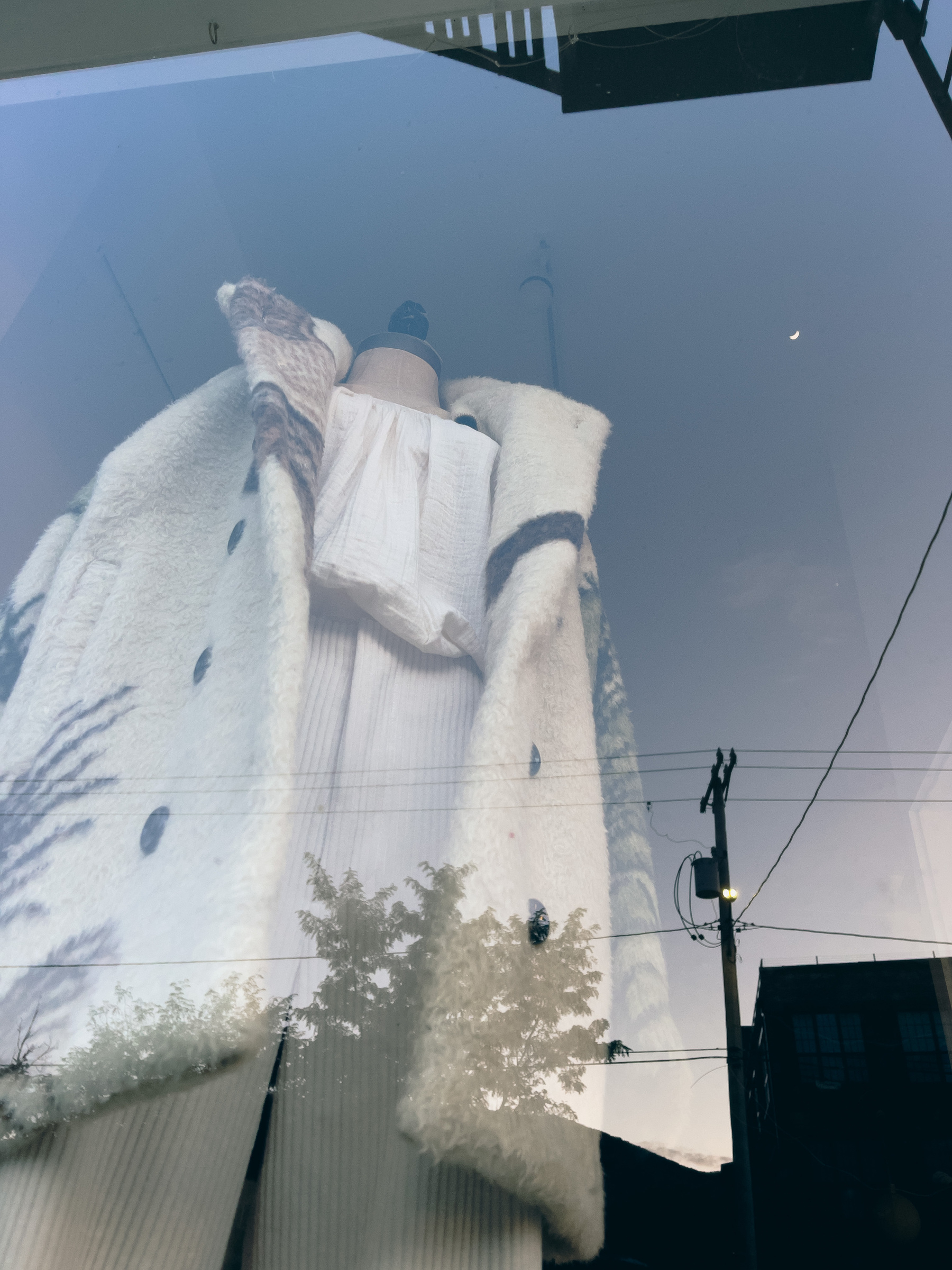 Off white corduroy pants, linen blouse and fleece jacket on a mannequin in a shop window. Building’s and moon reflections overlaid.