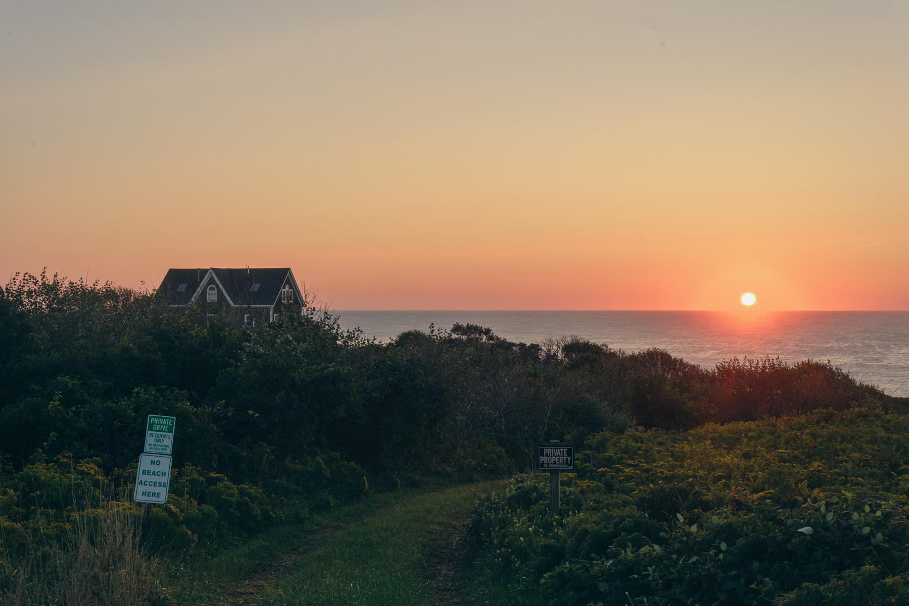 Landscape with house and ocean in the distance. Sun coming up.