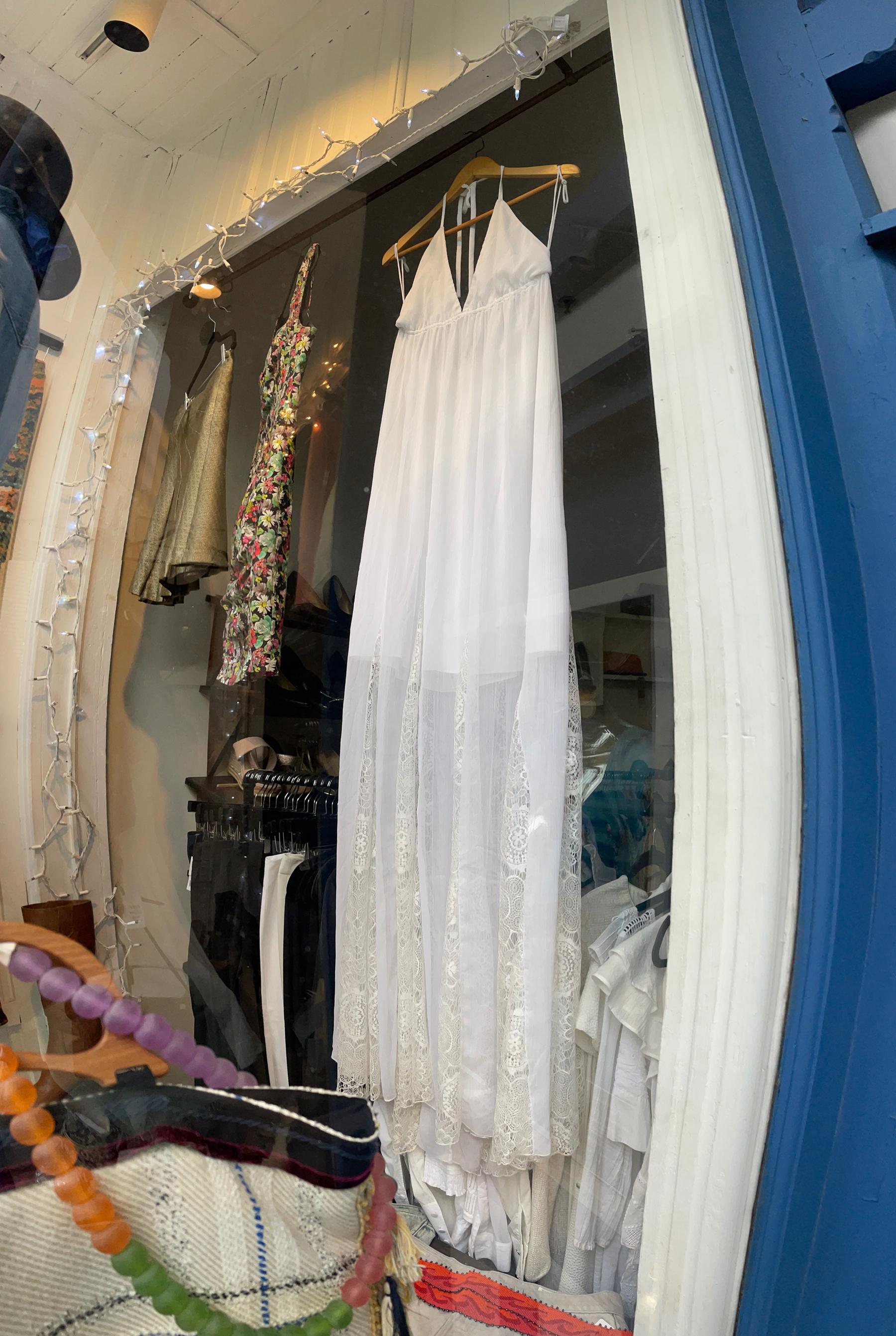 Long white sheer summer dress on display in shop window.
