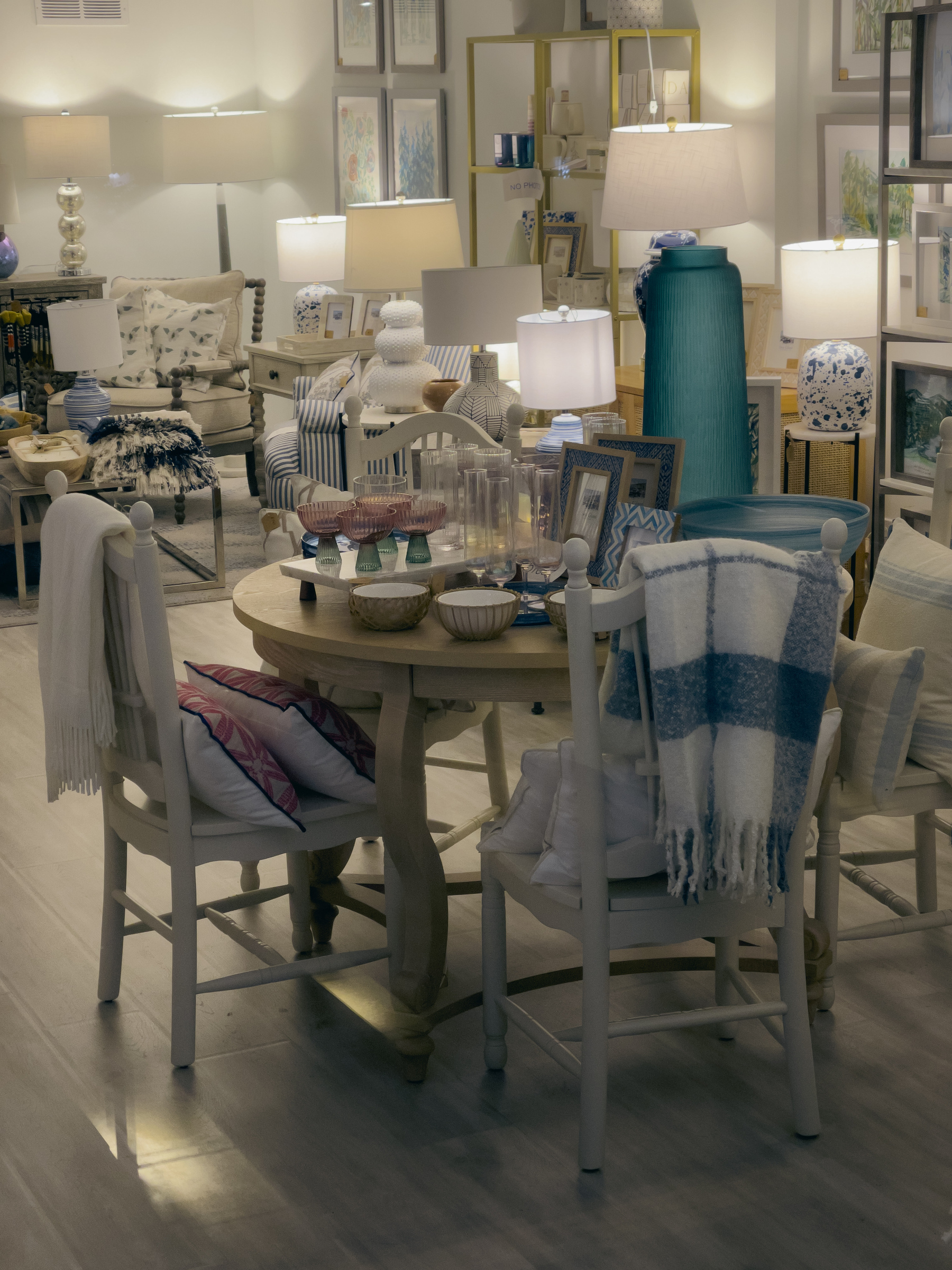 Interior of a home furnishings store, pastel tones dominate, scene lit by a multitude of rable lamps.