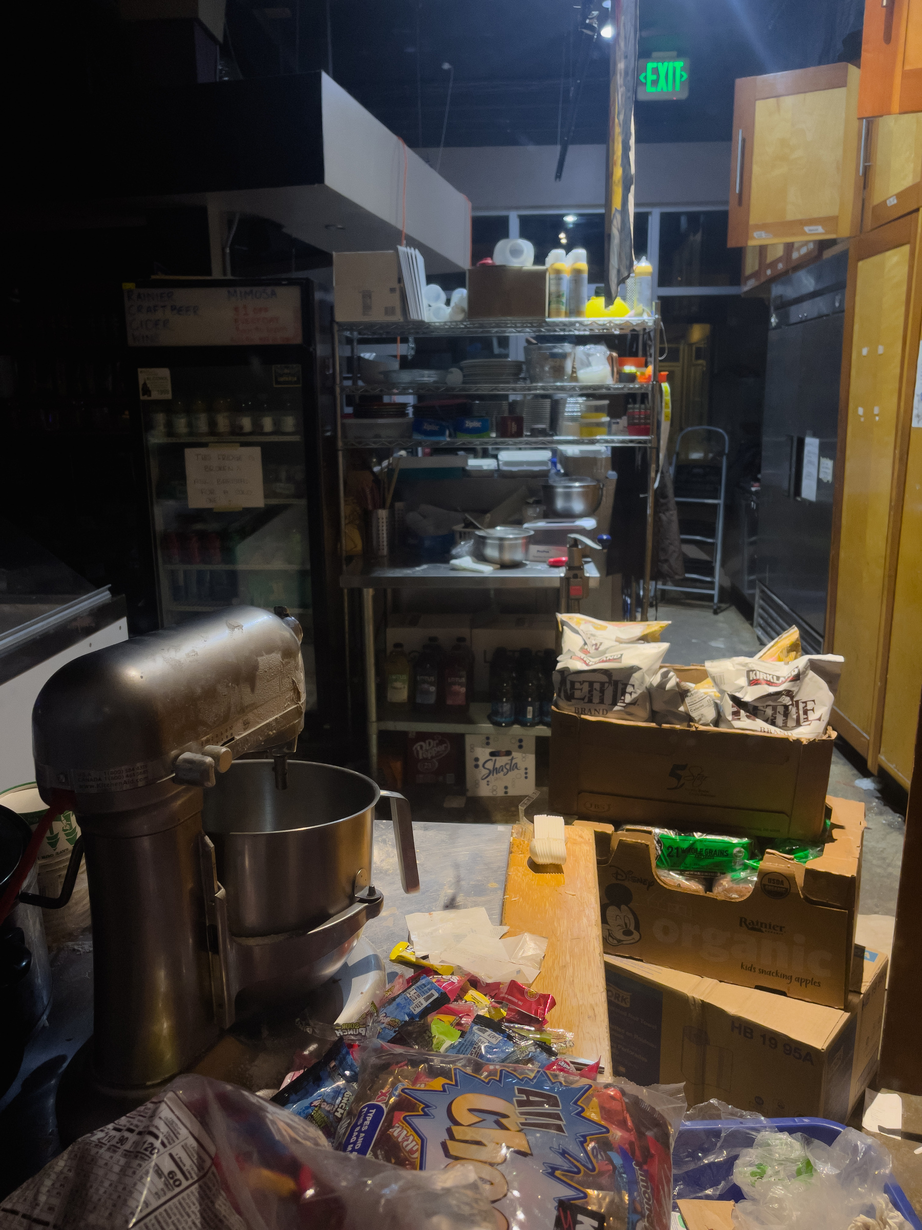 Interior of messy restaurant kitchen with stand mixer in the left foreground.