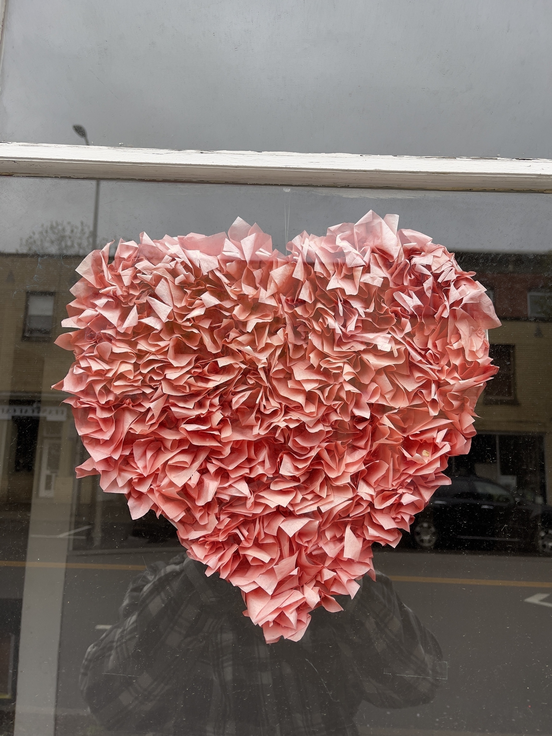 Frilly pink heart hanging in shop window.