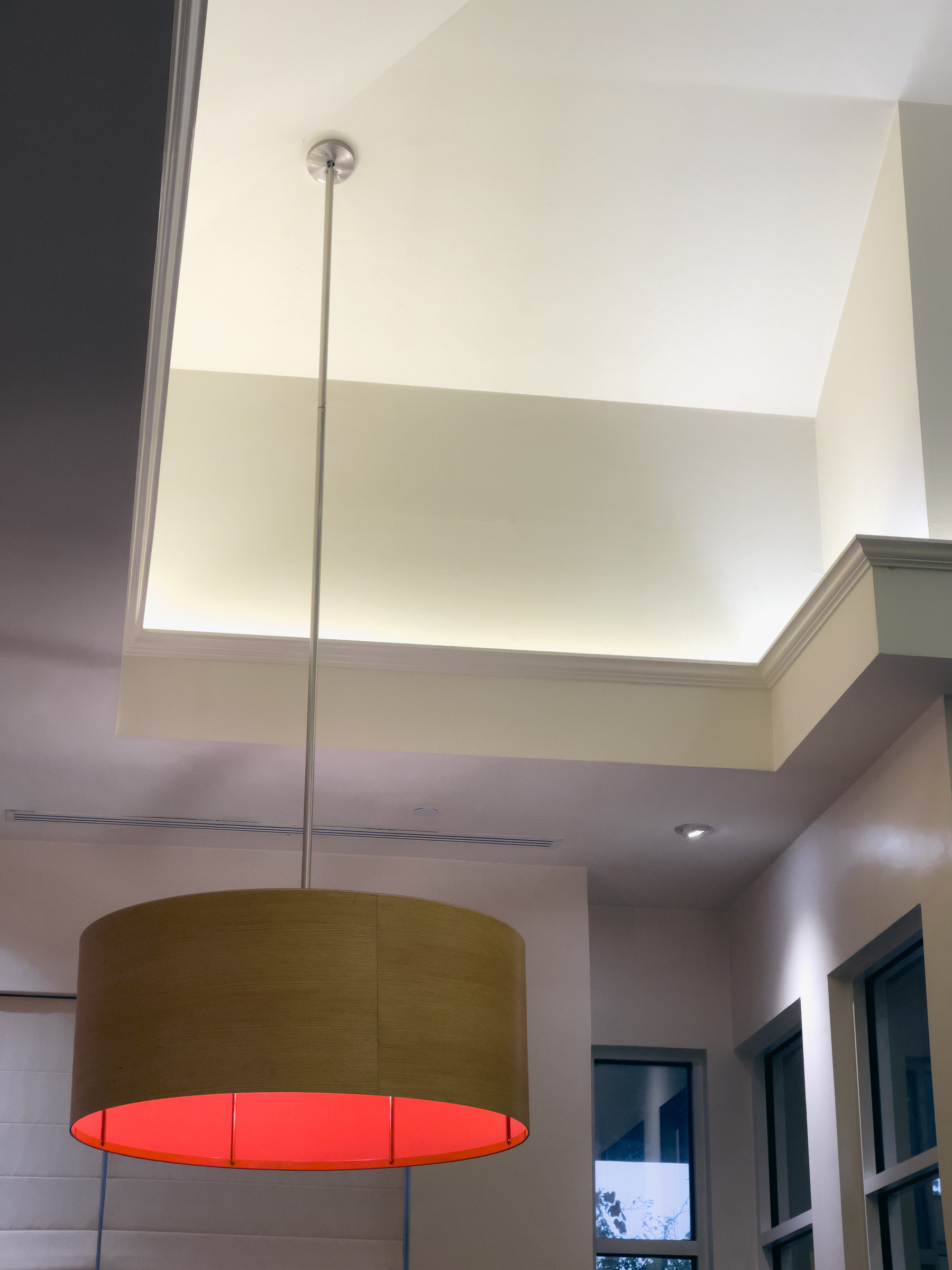 Pendant light fixture in hotel lobby space glowing red.