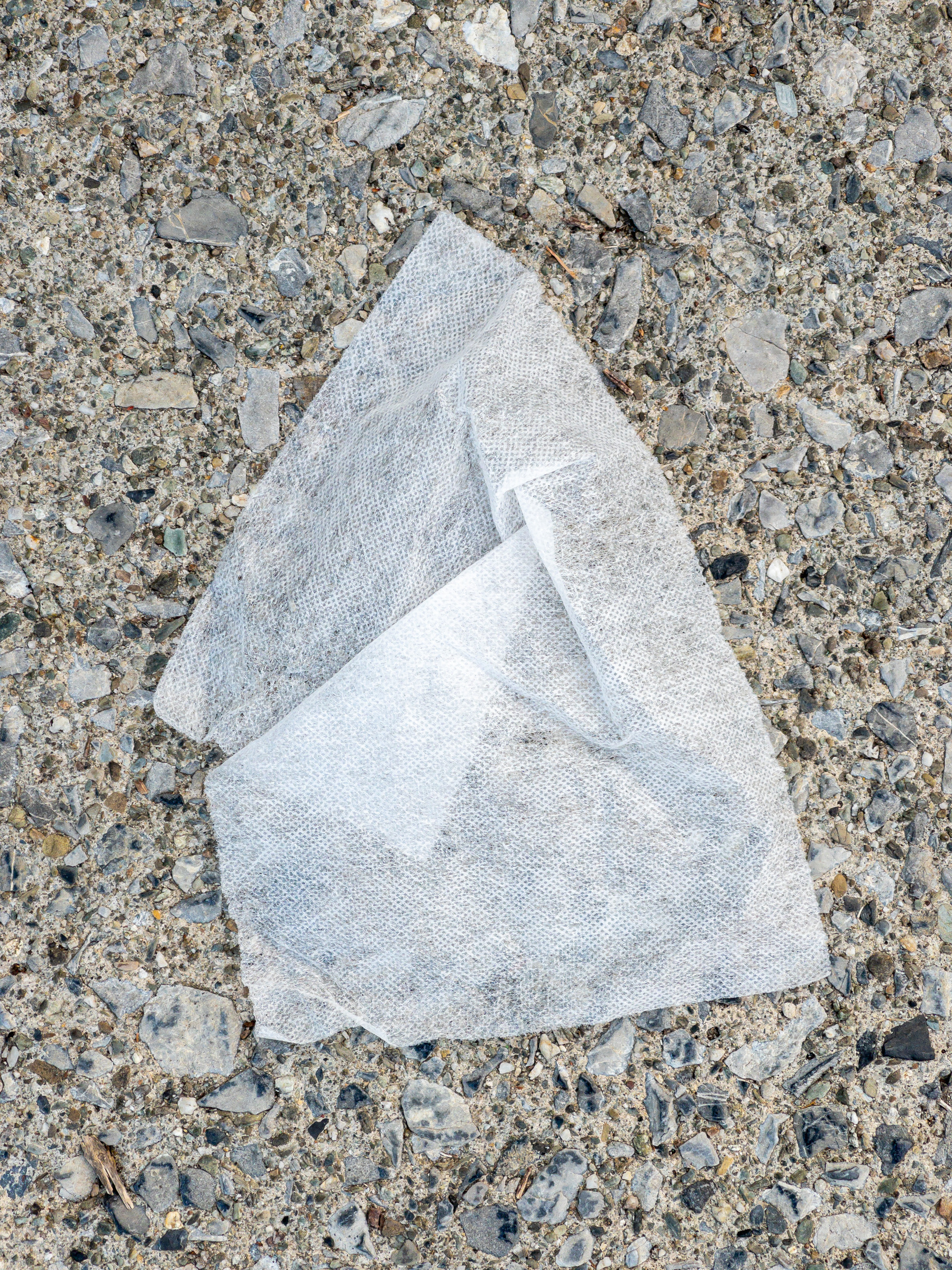 White paper detritus on the sidewalk crumpled in an interesting shape.