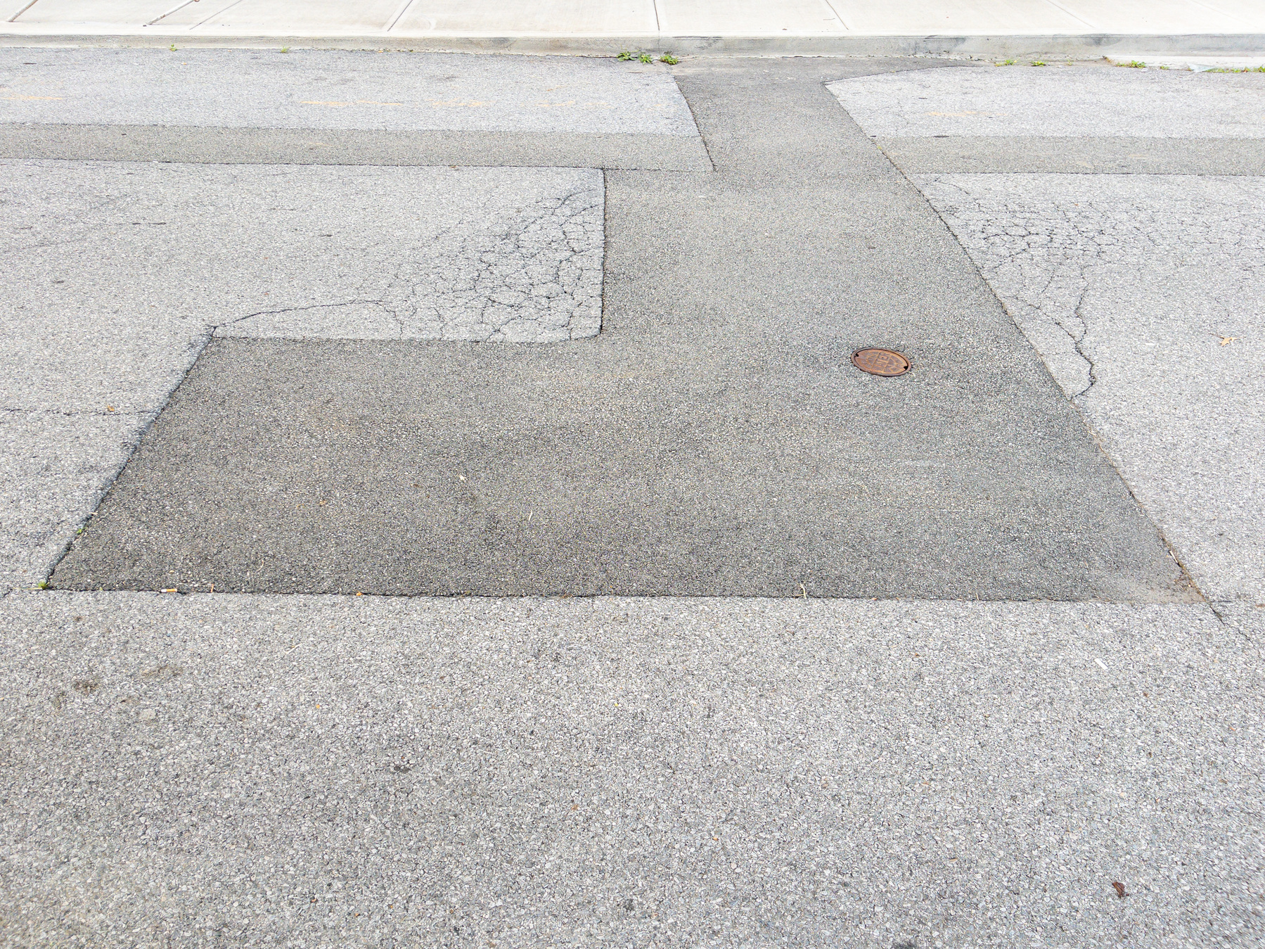 Rectilinear patching in asphalt street surface.