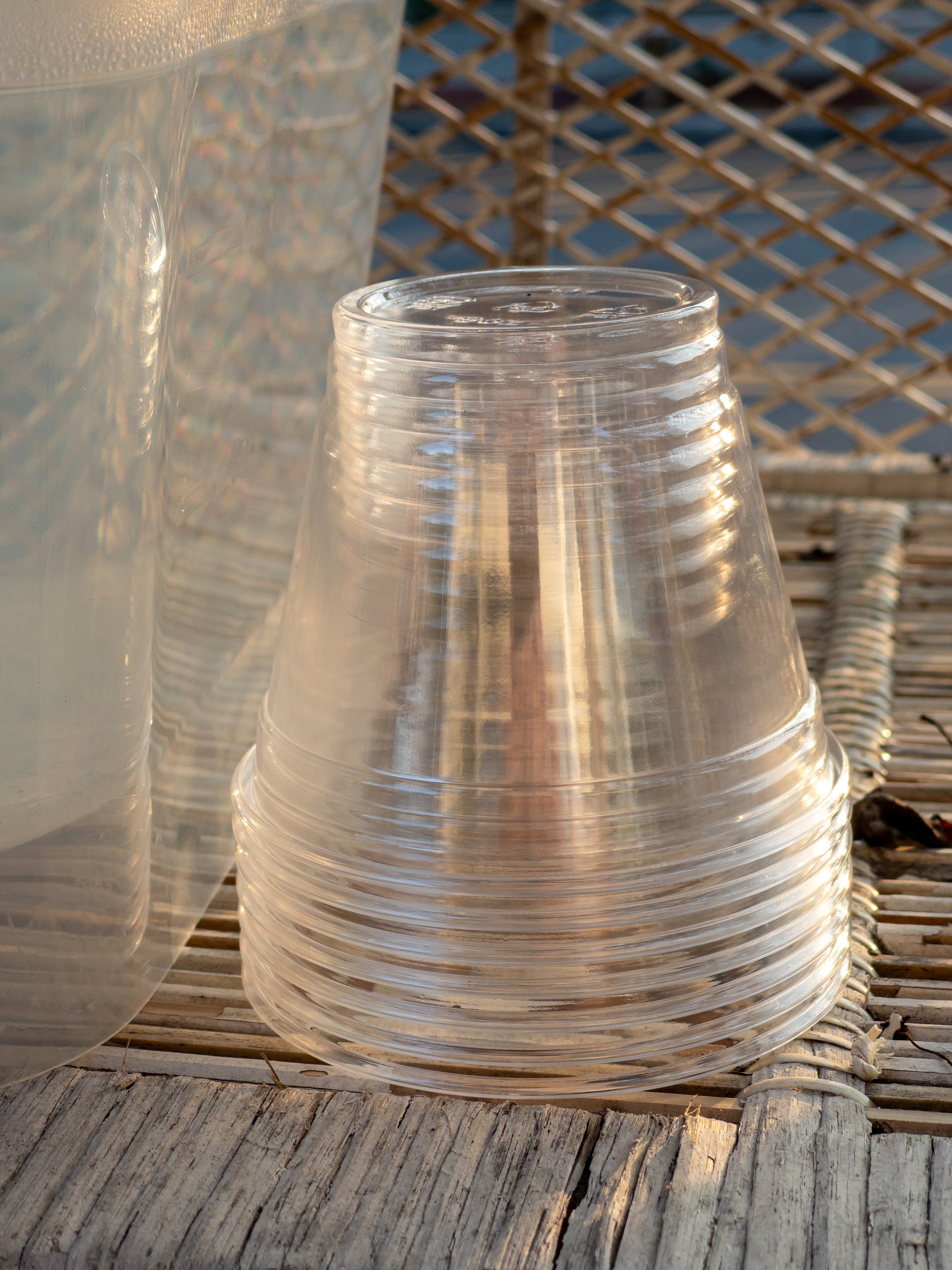 Stack of clear plastic cups on a wicker shelf.