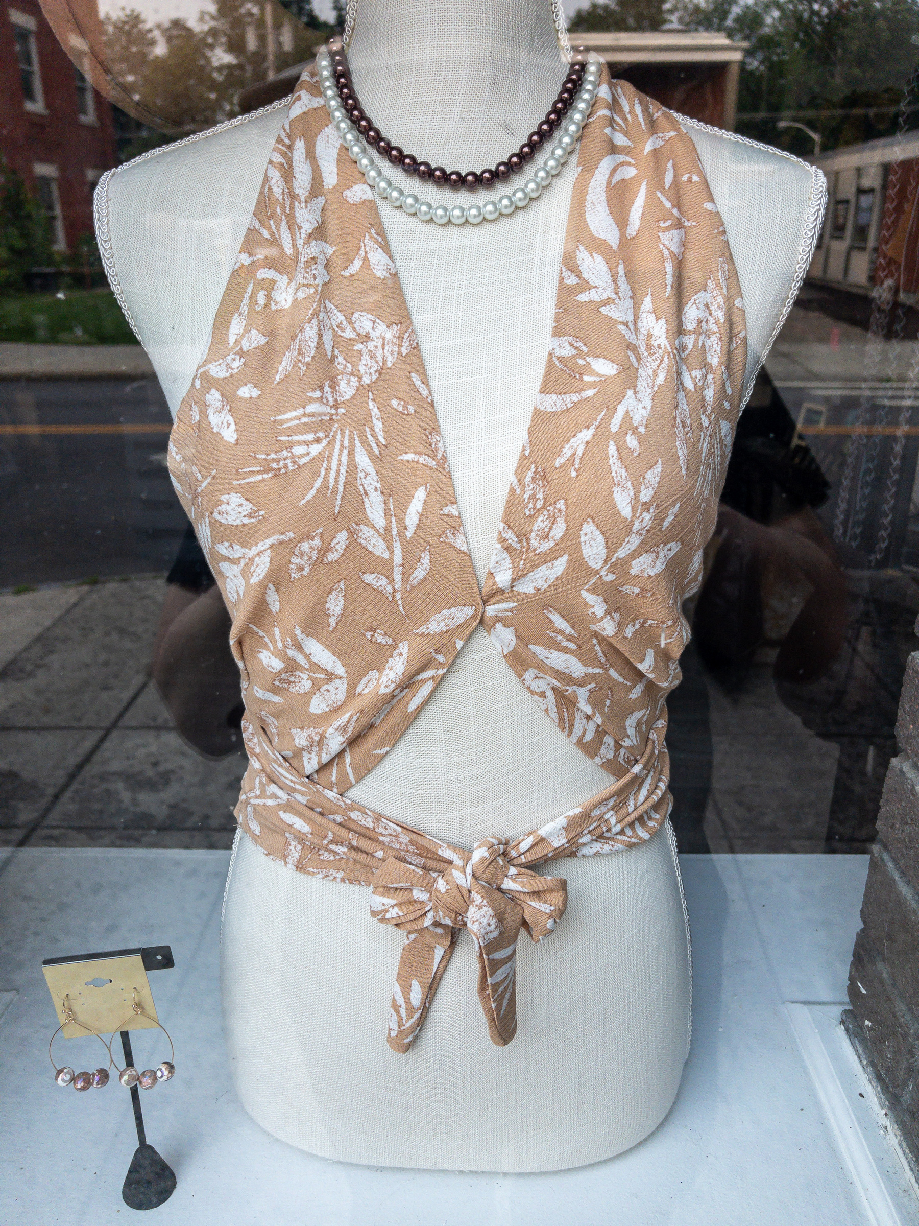 Beige floral print halter top on a female bust in a shop window.