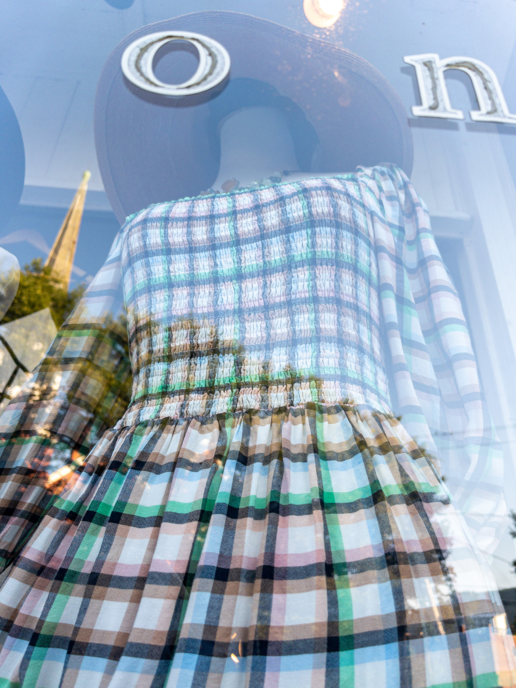 Brown, black and blue plaid dress on a mannequin in a shop window.