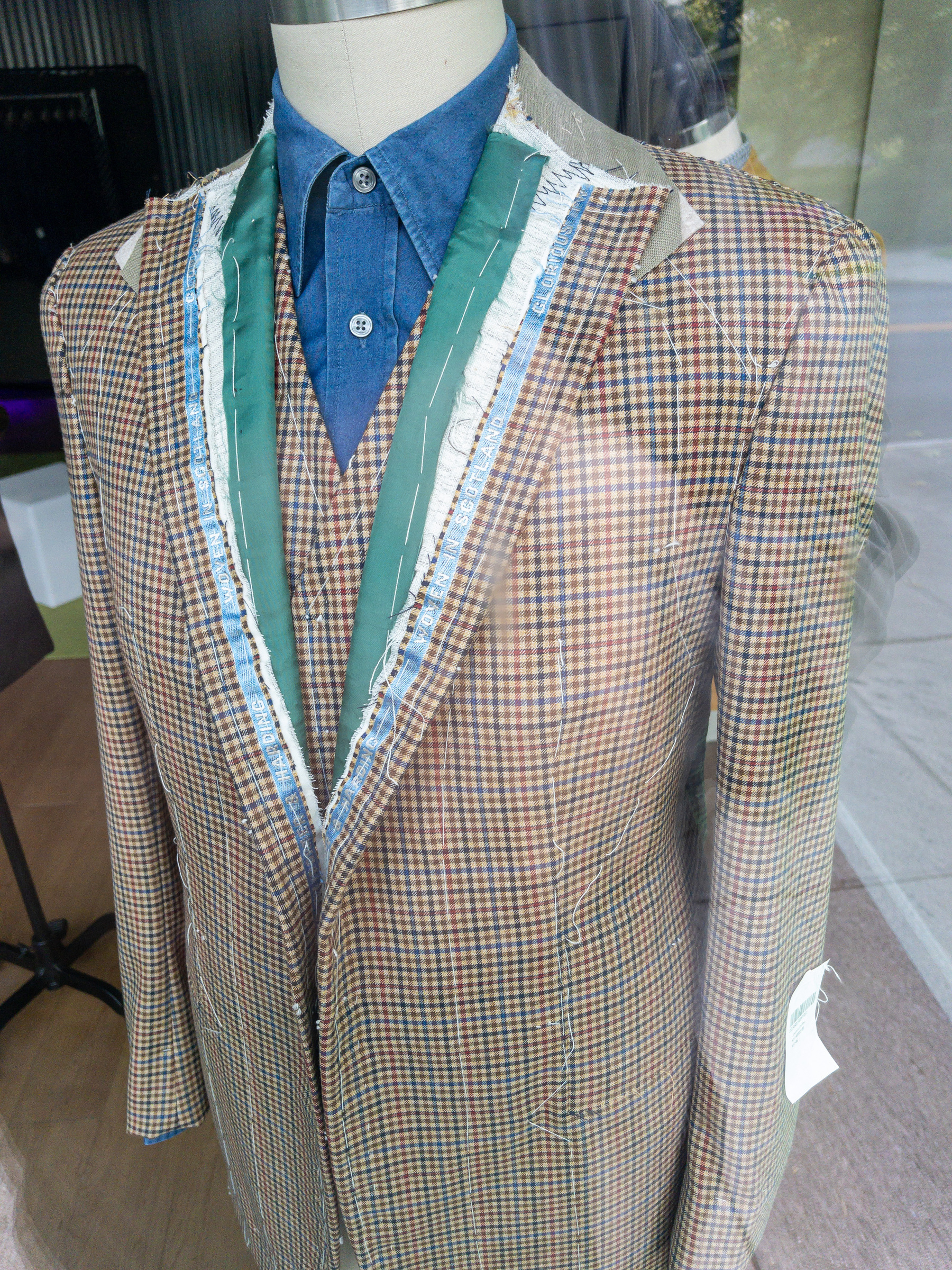 Partially finished men’s plaid dress jacket in a tailor shop window.