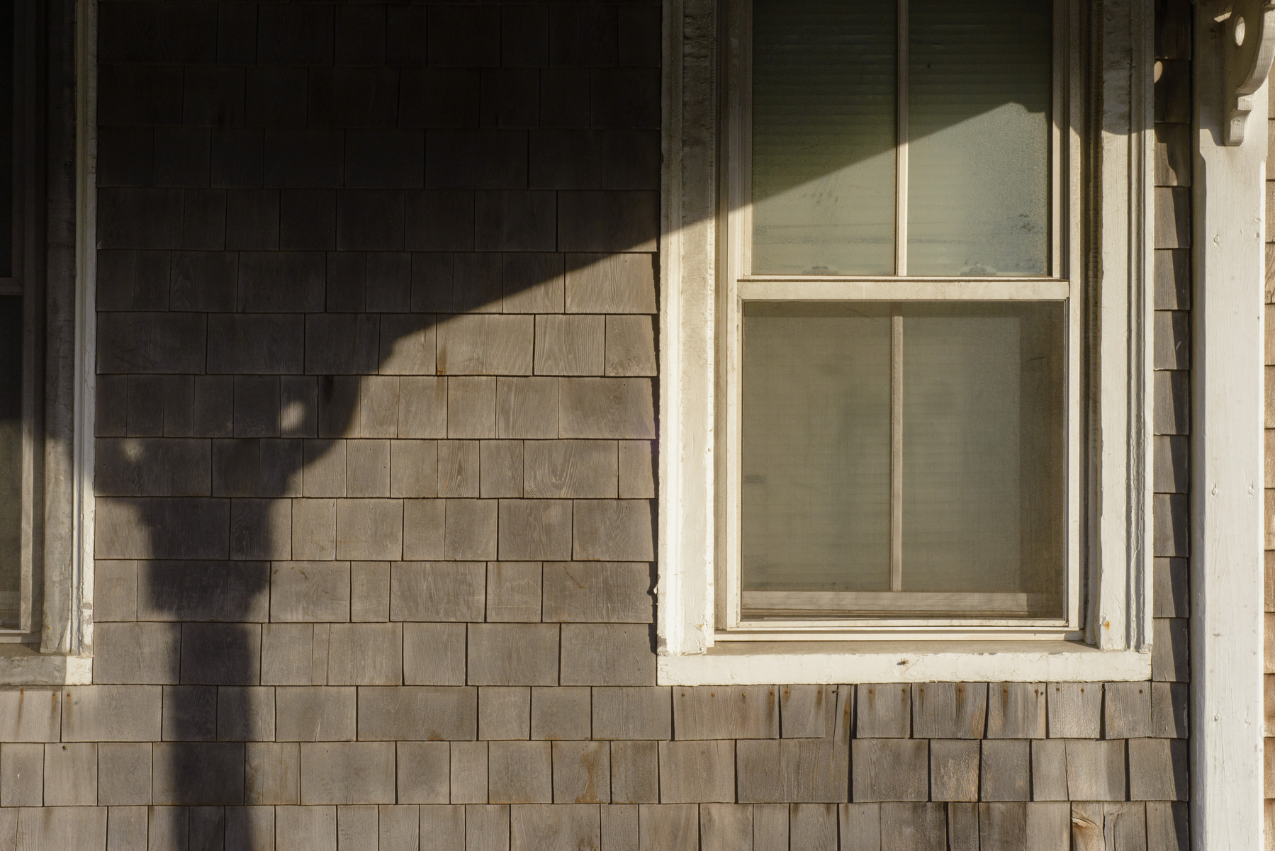Sunlight and shadow on cedar shake wall and window.