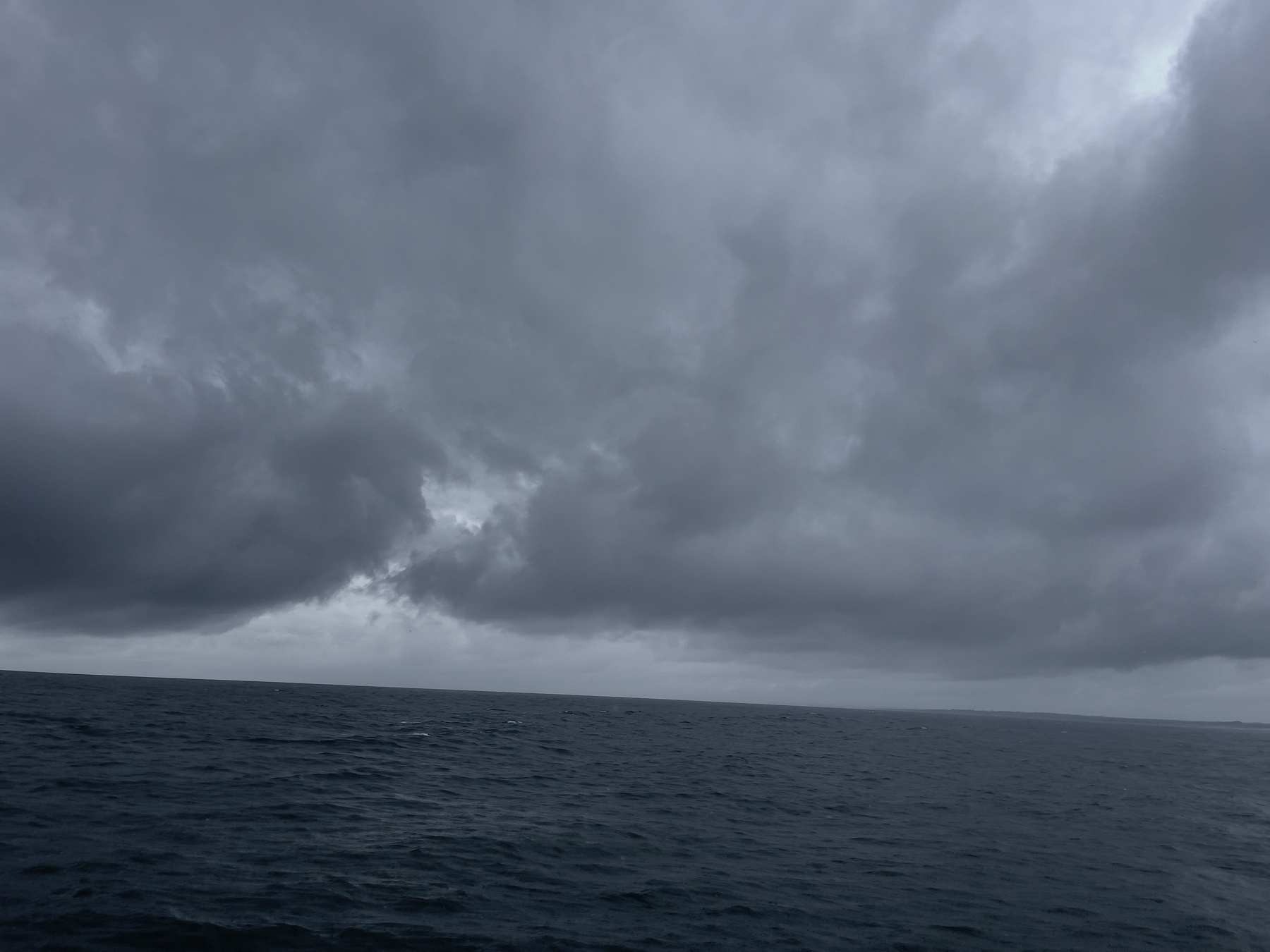 Ocean and storm clouds, horizon line tilted up to the left.