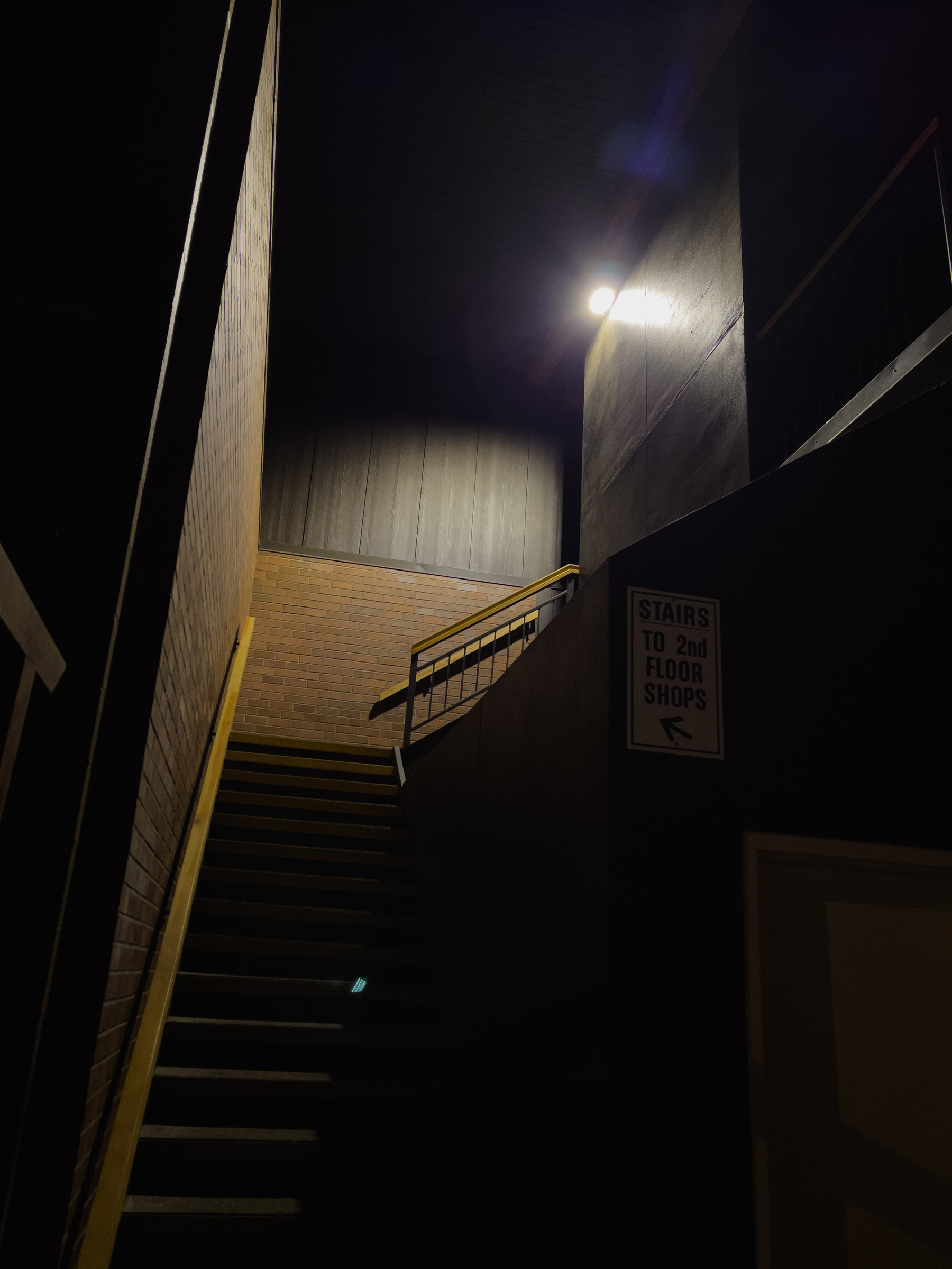 Exterior stairway to second floor of a commercial building at night lit by a security light.