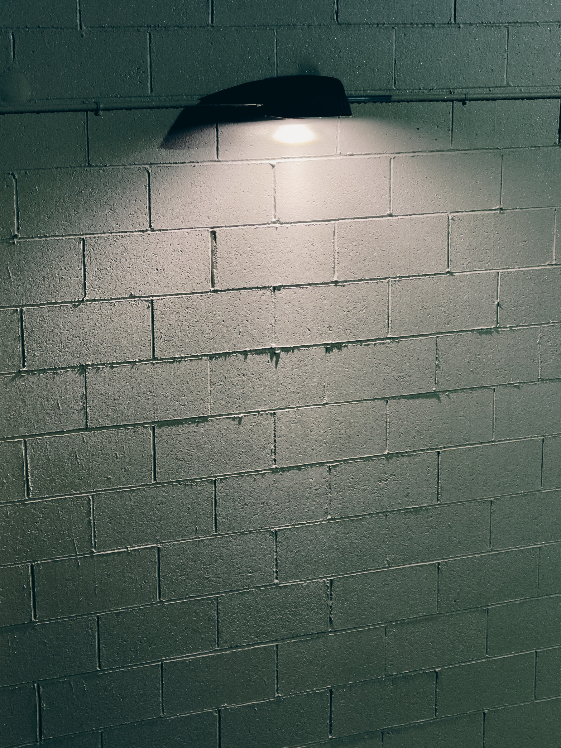 Security light attached to concrete block wall, illuminating it and picking out the joints between the blocks.