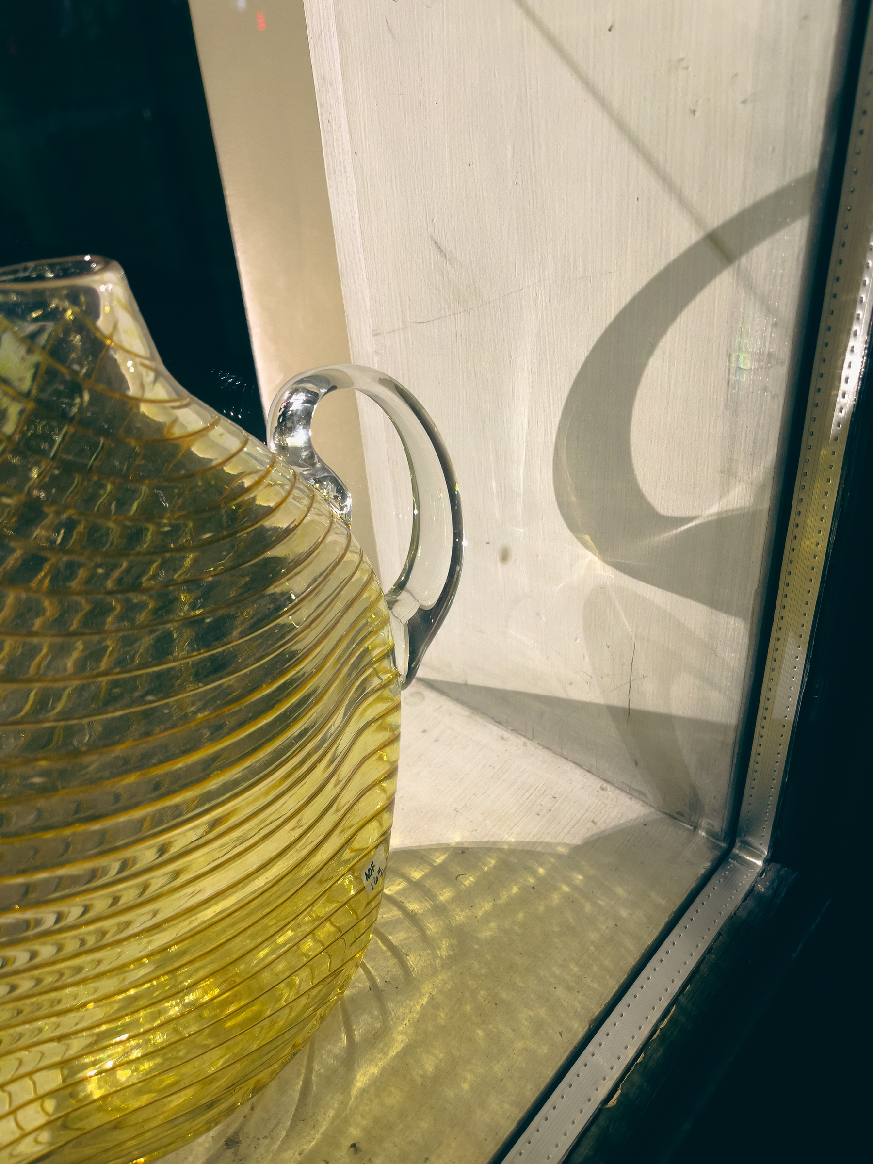 Art glass pitcher in a shop window display.
