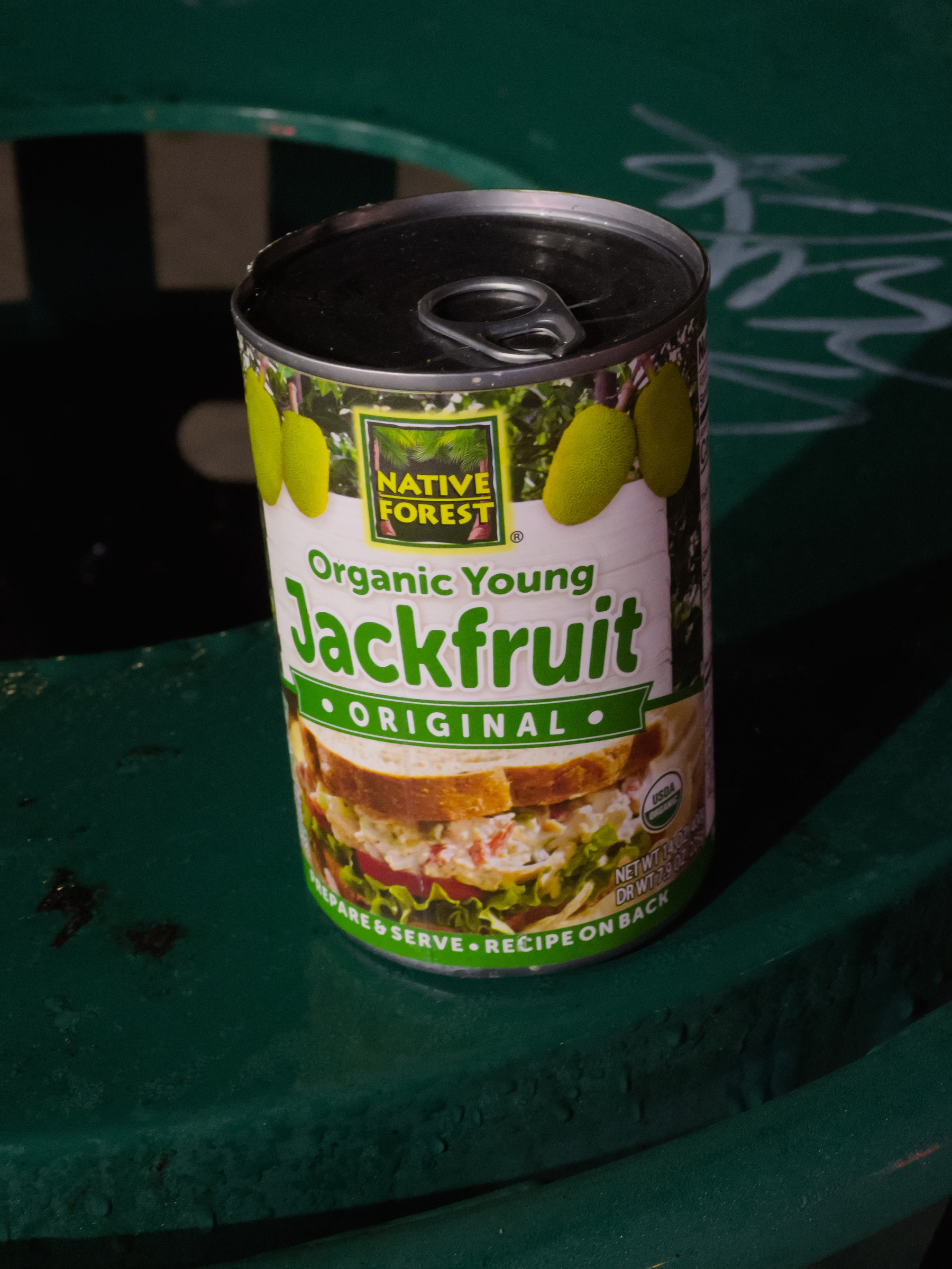 Unopened can of organic jackfruit sitting on a trash receptacle.