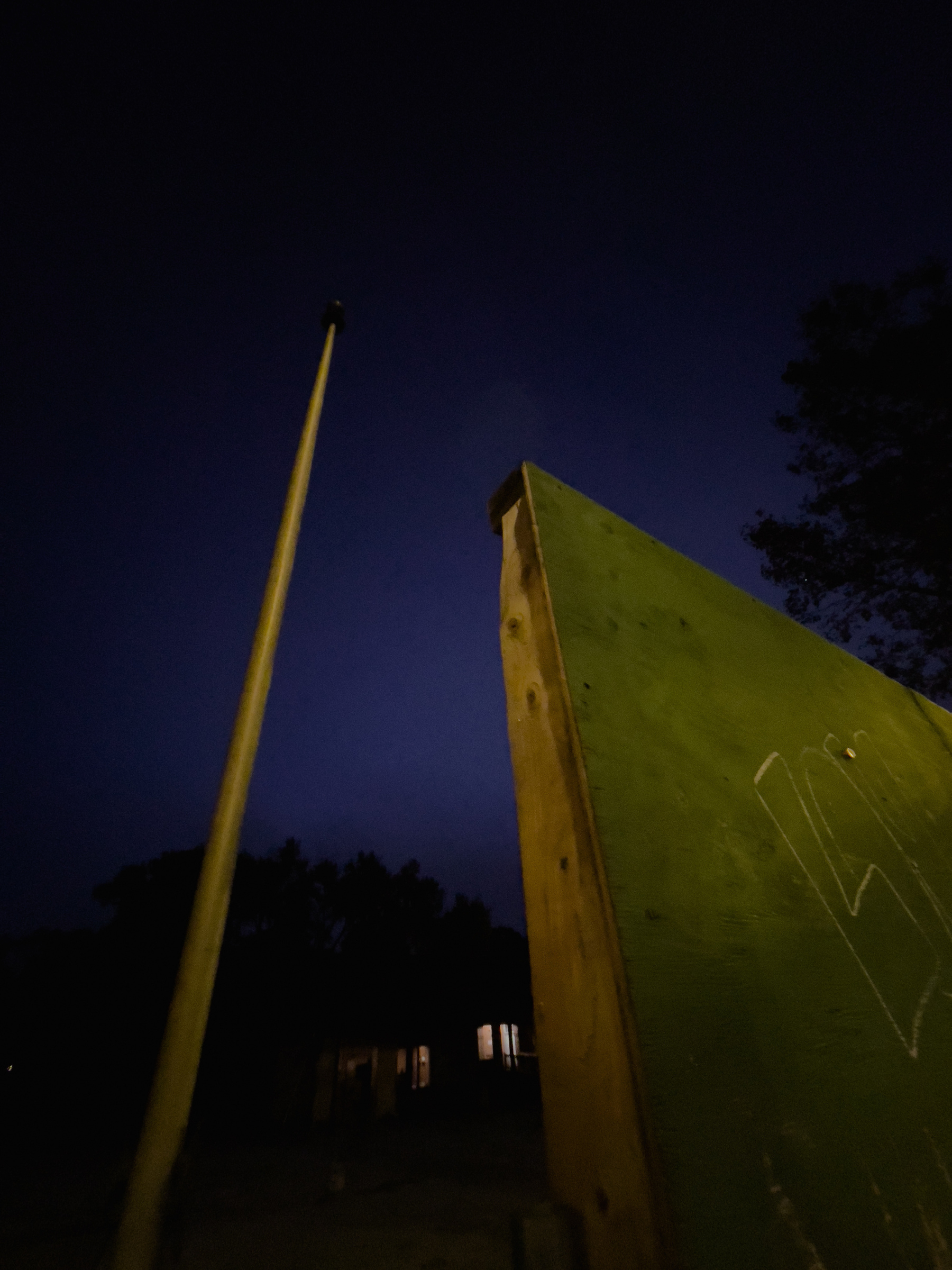 Flagpole and plywood construction fencing illuminated by streetlights.