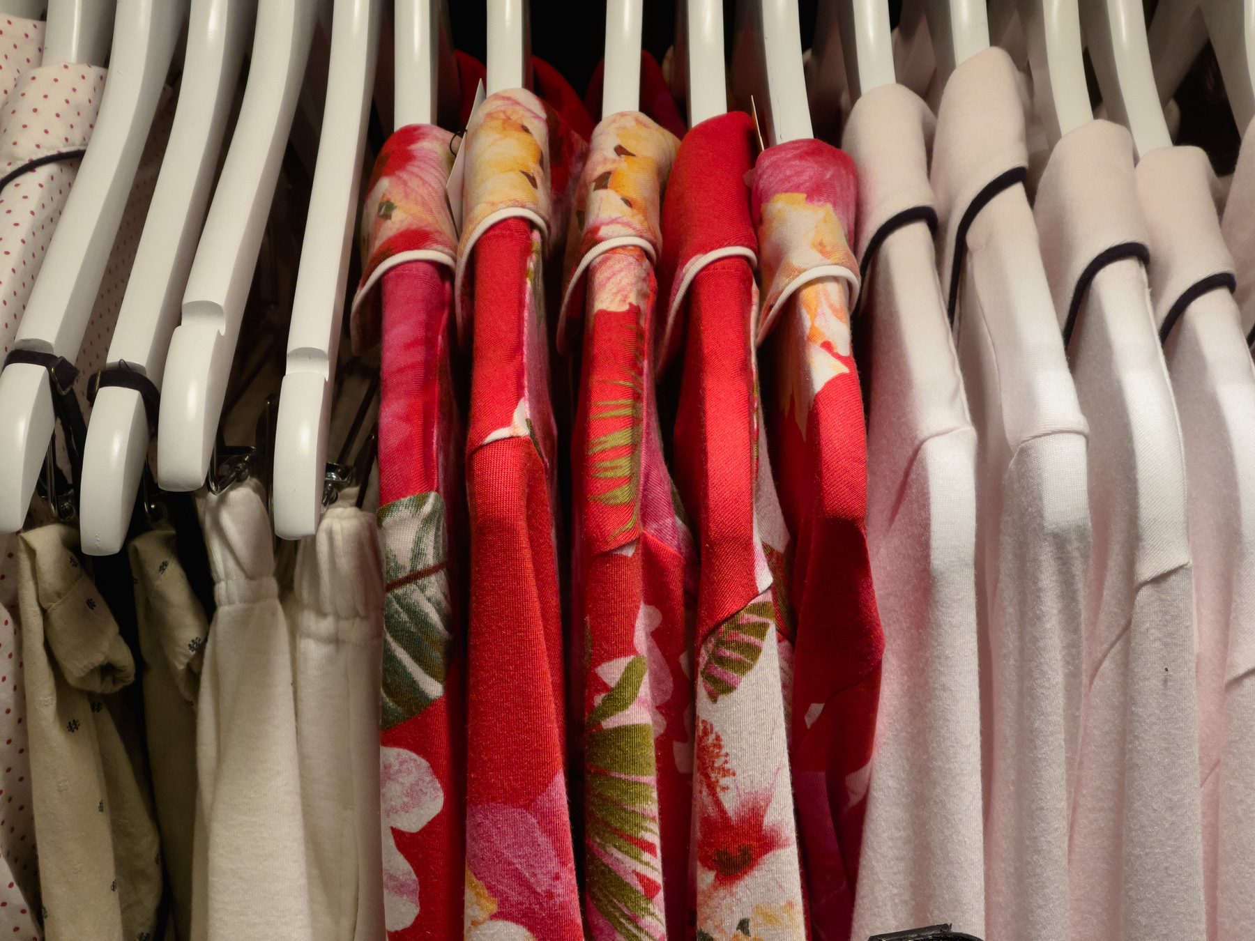 Dresses on dress rack, red in the middle, white at the ends.