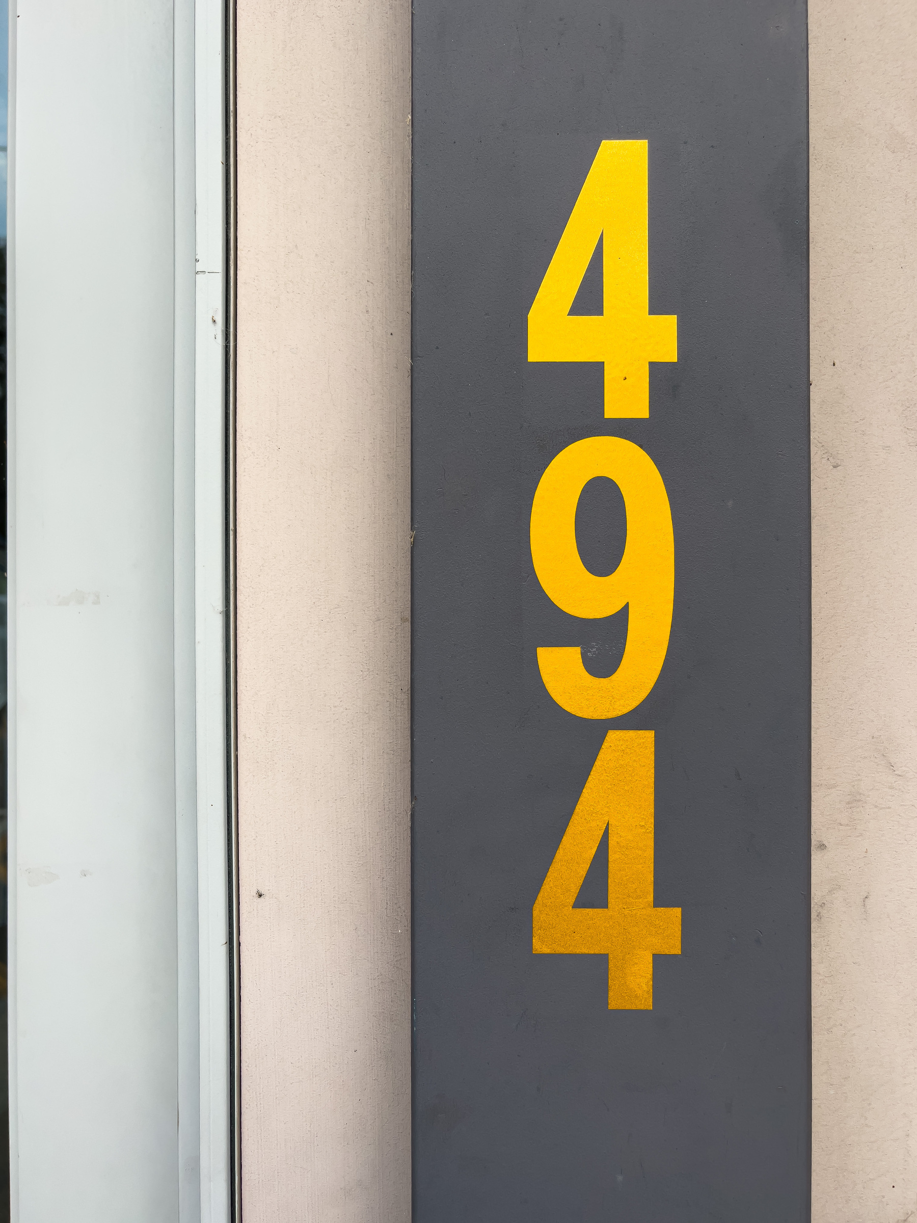 494 house number painted in yellow on door jamb painted gray.
