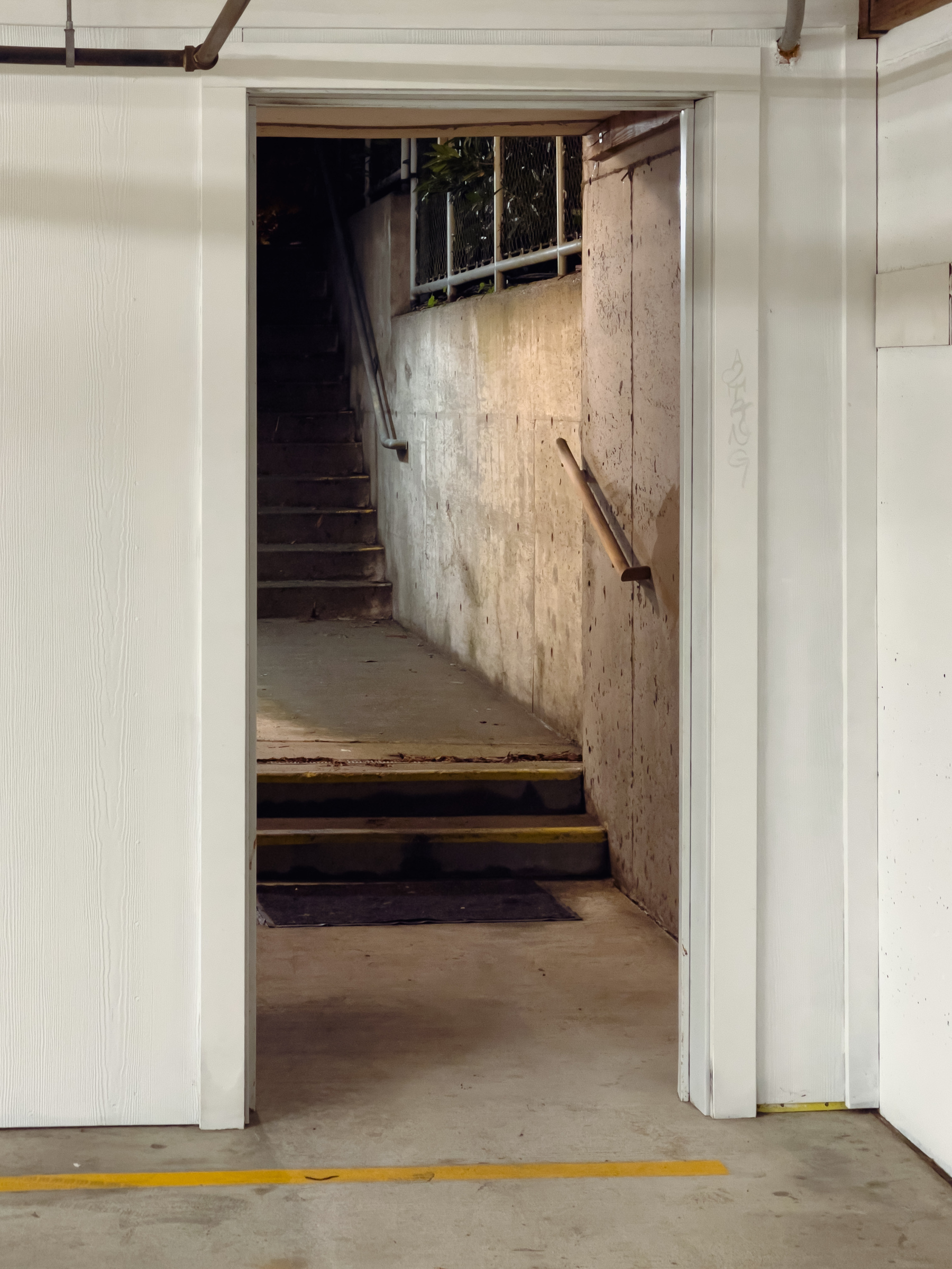 Descending concrete stairs through a doorway in a white wall.