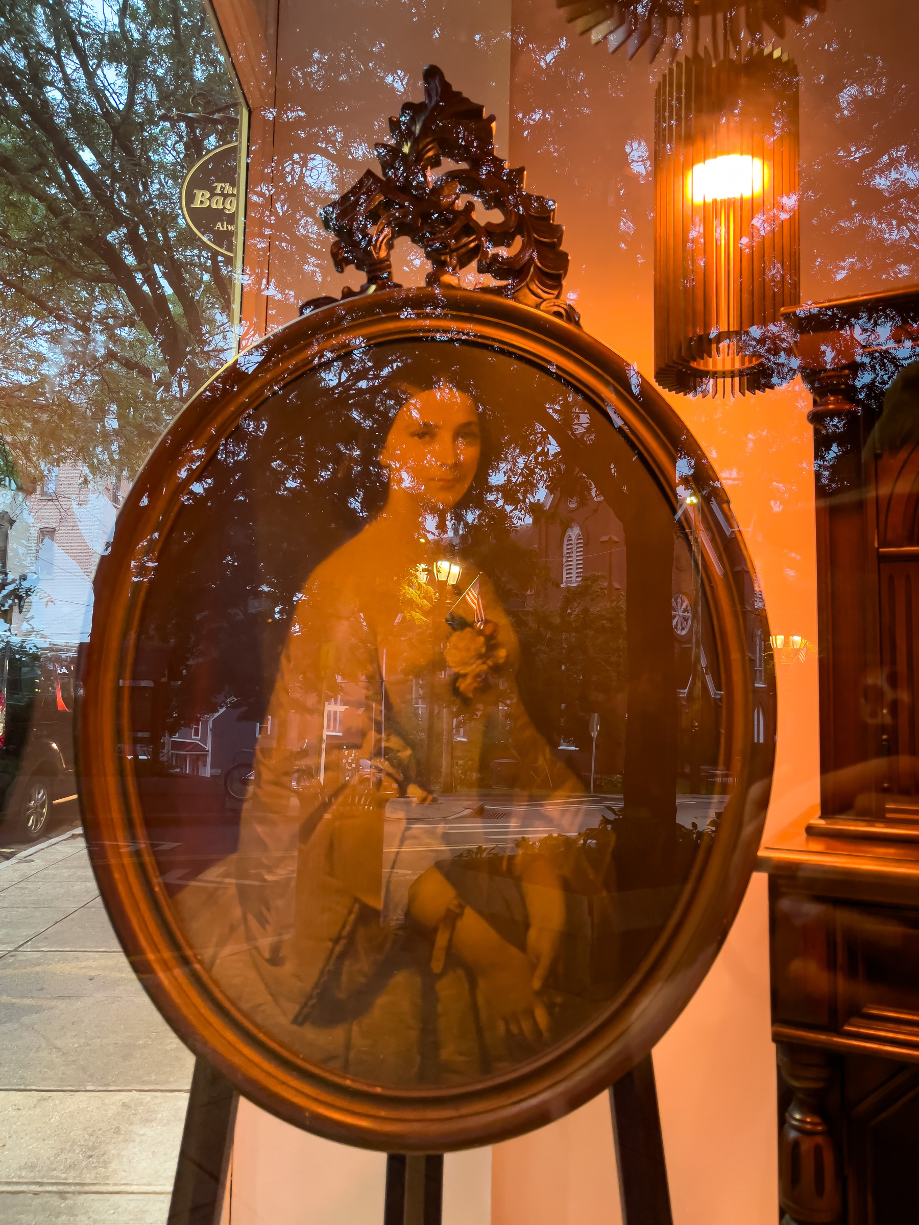 Painting of woman in Colonial/Victorian dress. Oval frame and canvas. In an antique shop window.