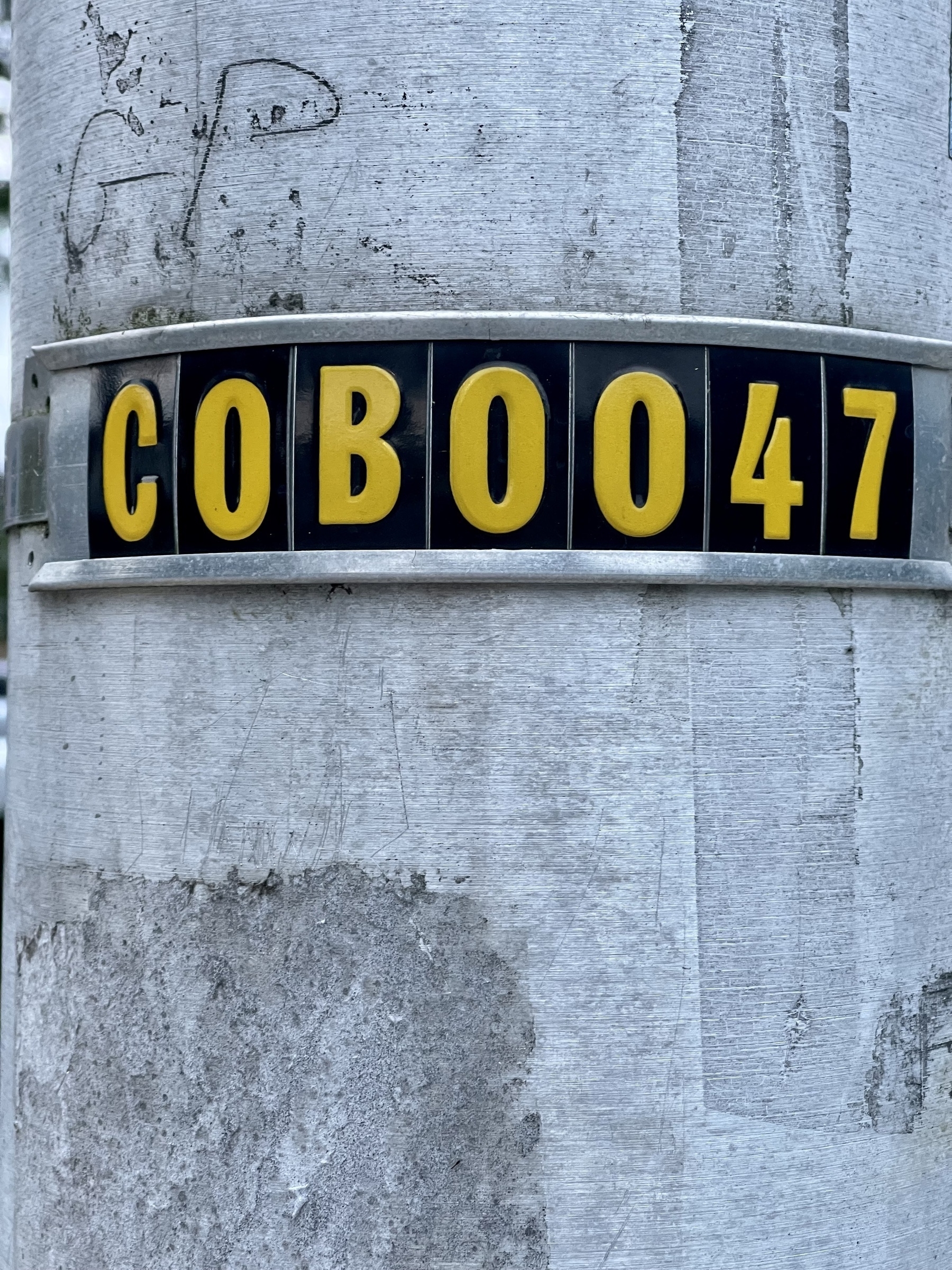COB0047 metal identification plate on a metal utility pole.