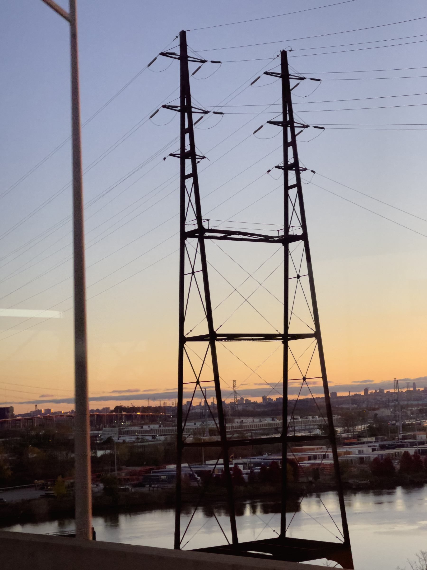 Transmission towers and wires with industrial landscape in background.