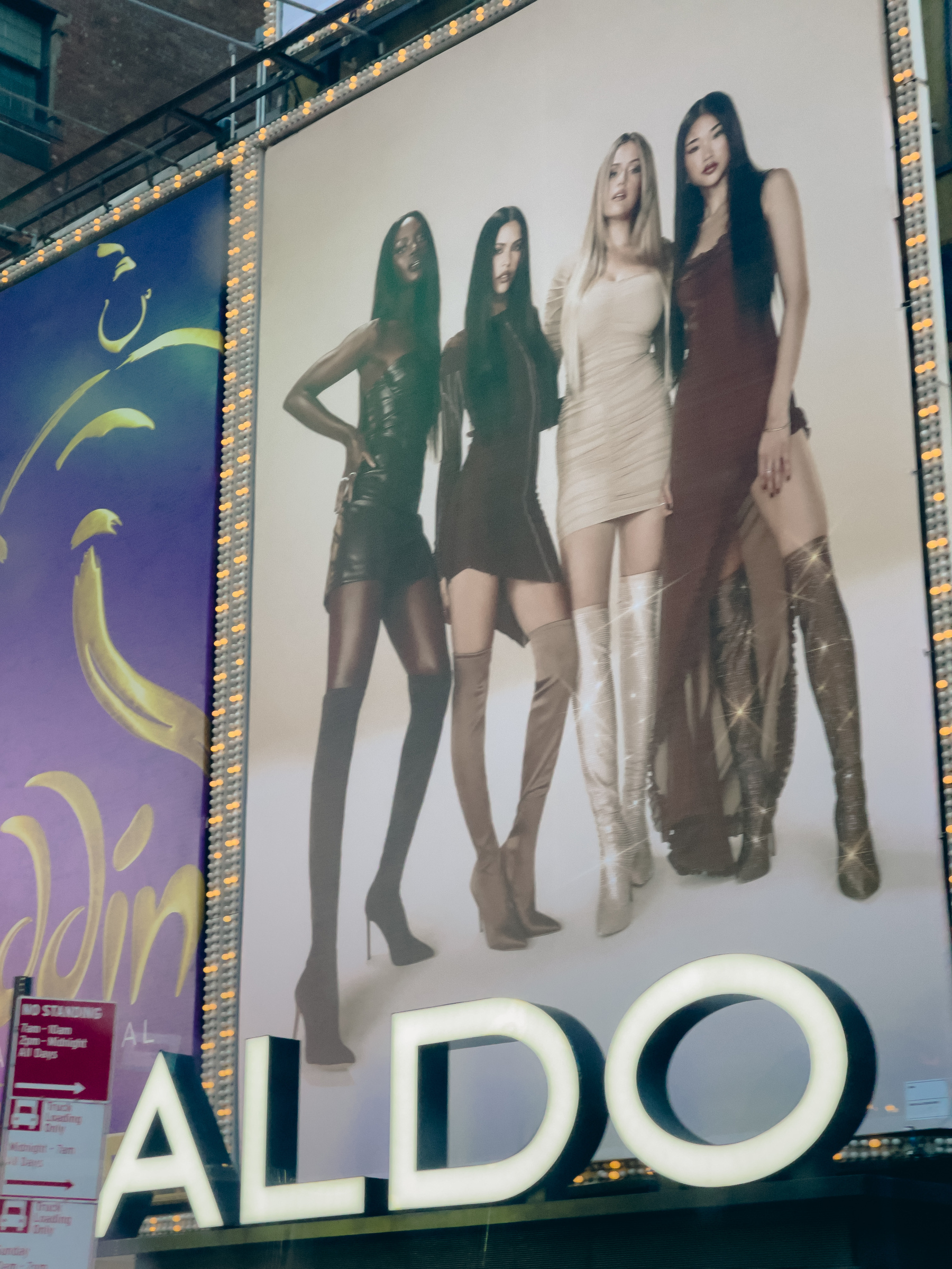 Electronic billboard with 4 women models wearing mini dresses, and ALDO in 3D letters at bottom.