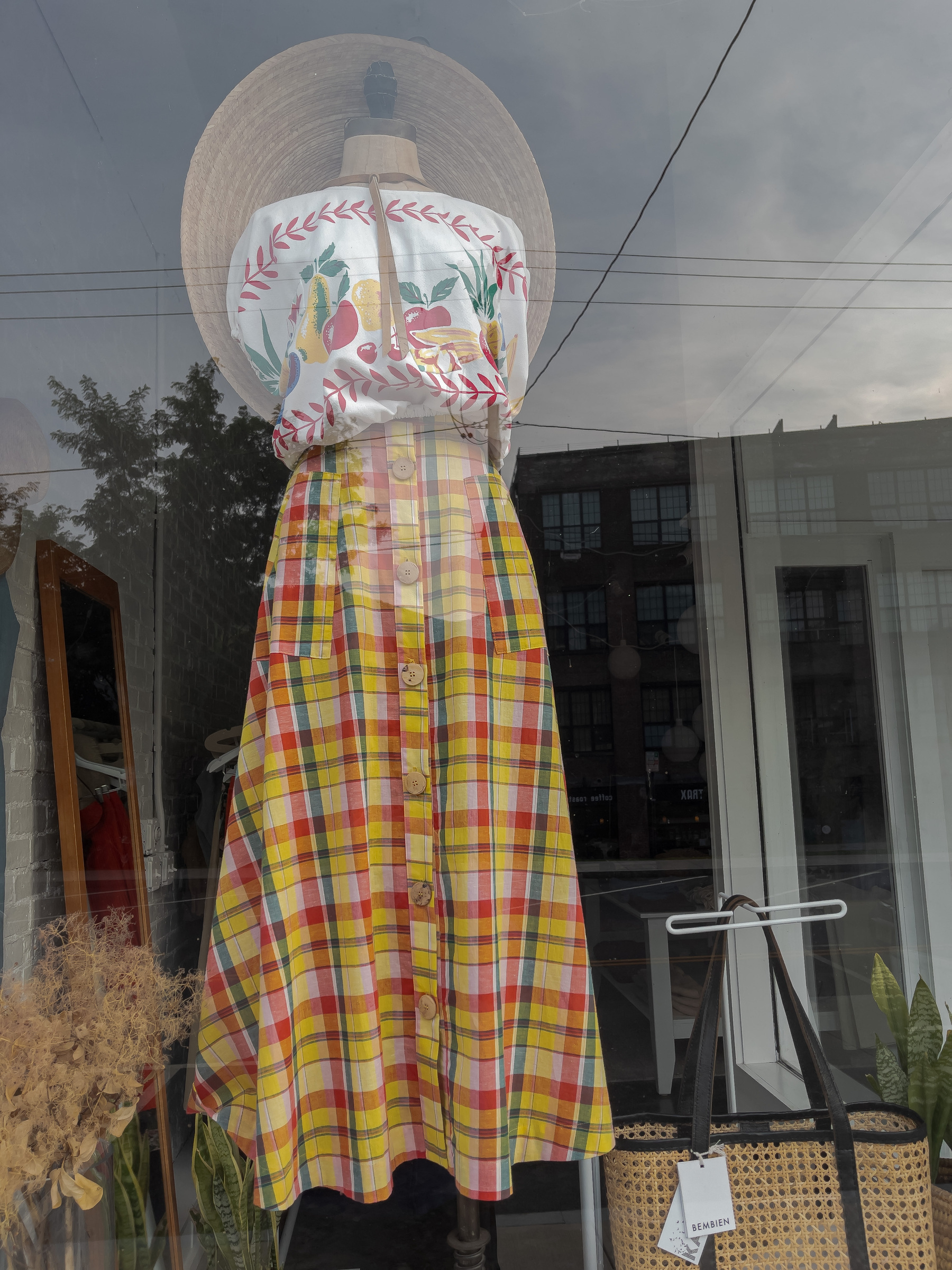 plaid skirt and peasant print blouse and large brimmed straw hat on mannequin form in shop window