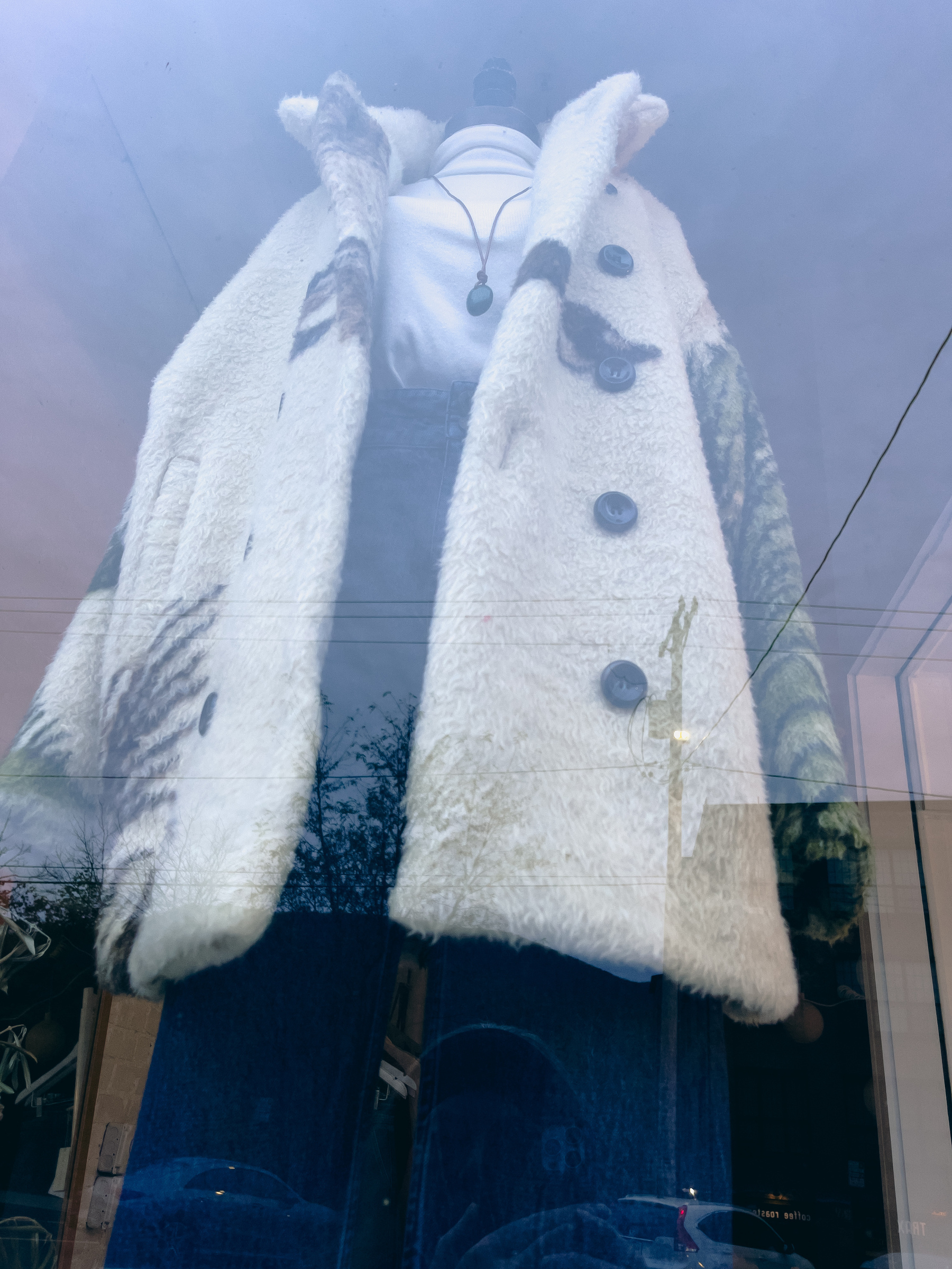 Woman’s fleece coat, knit top and blue jeans on mannequin in shop window. 