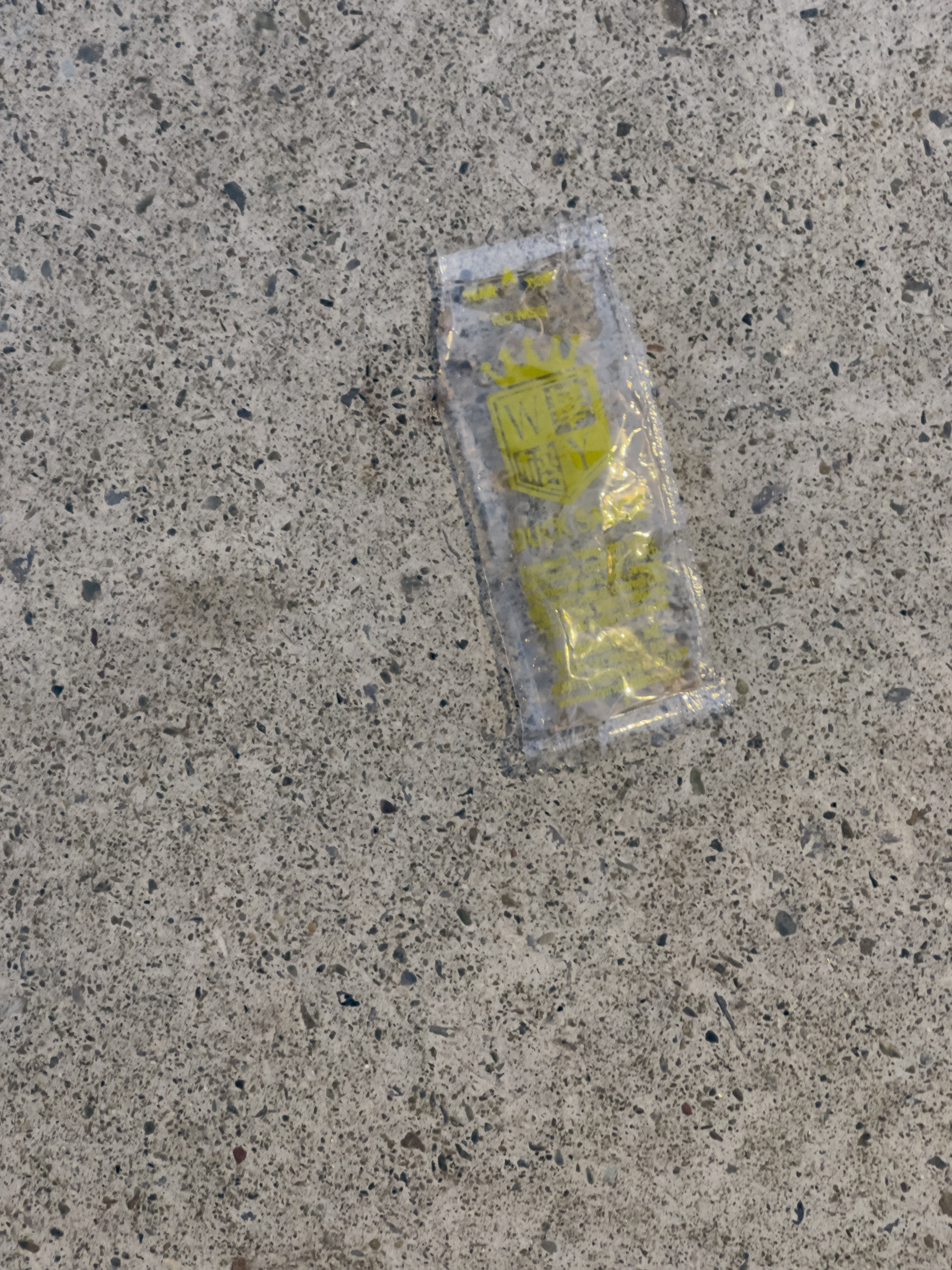 Empty chinese condiment package on concrete pavement.