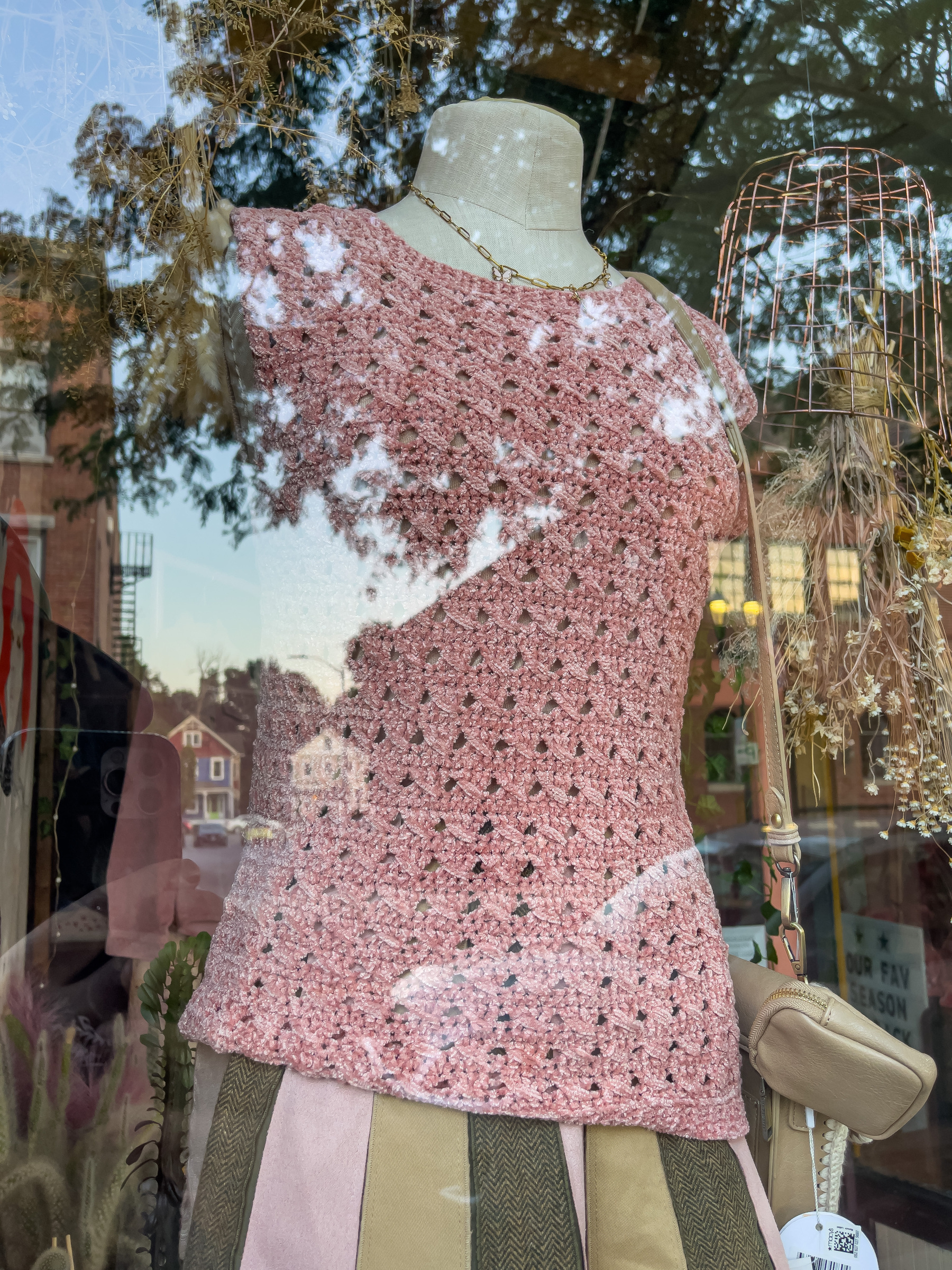 Woman’s pink knit top on mannequin in shop window.