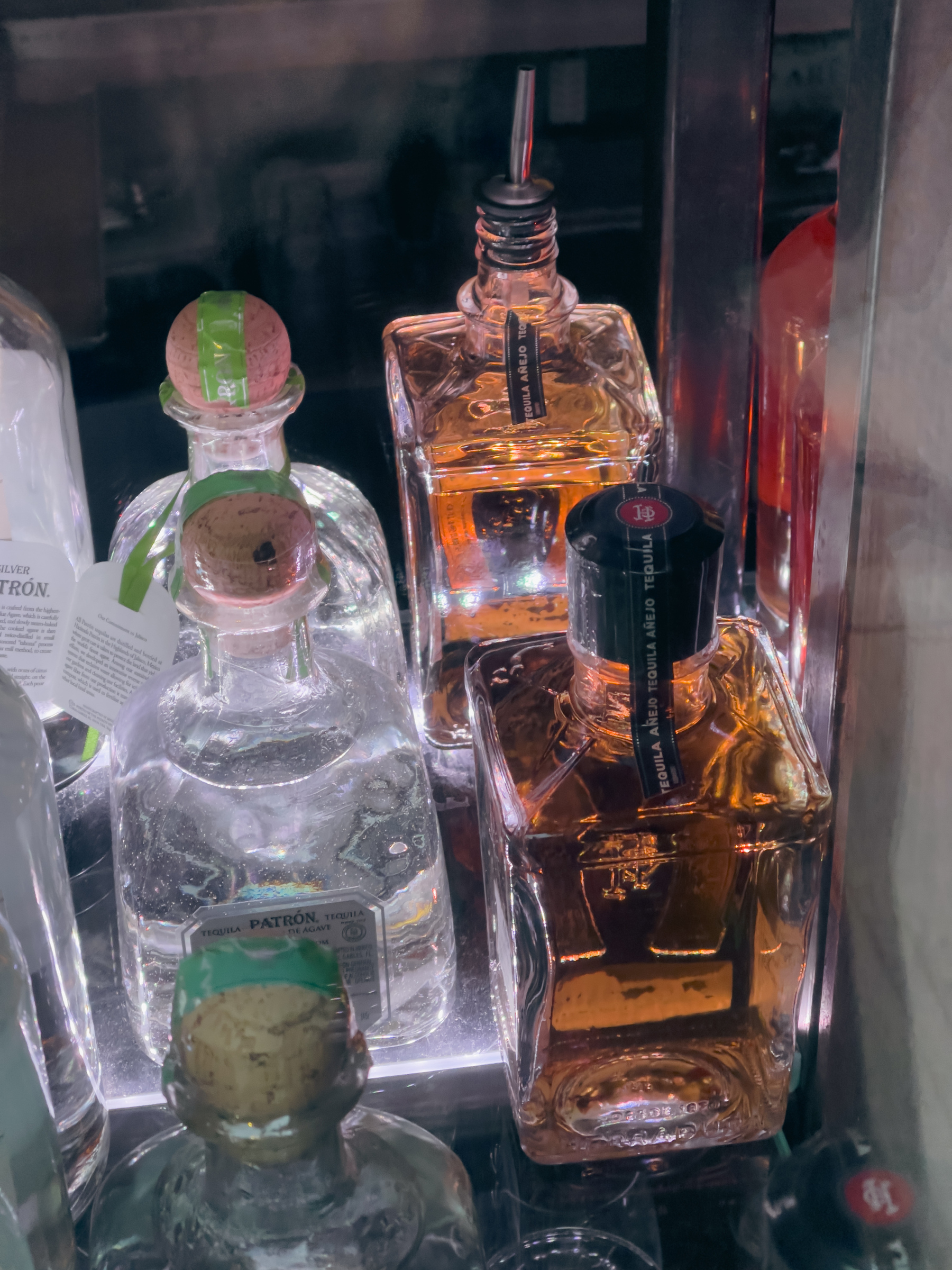 Liquor bottles in a bar window illuminated from below.