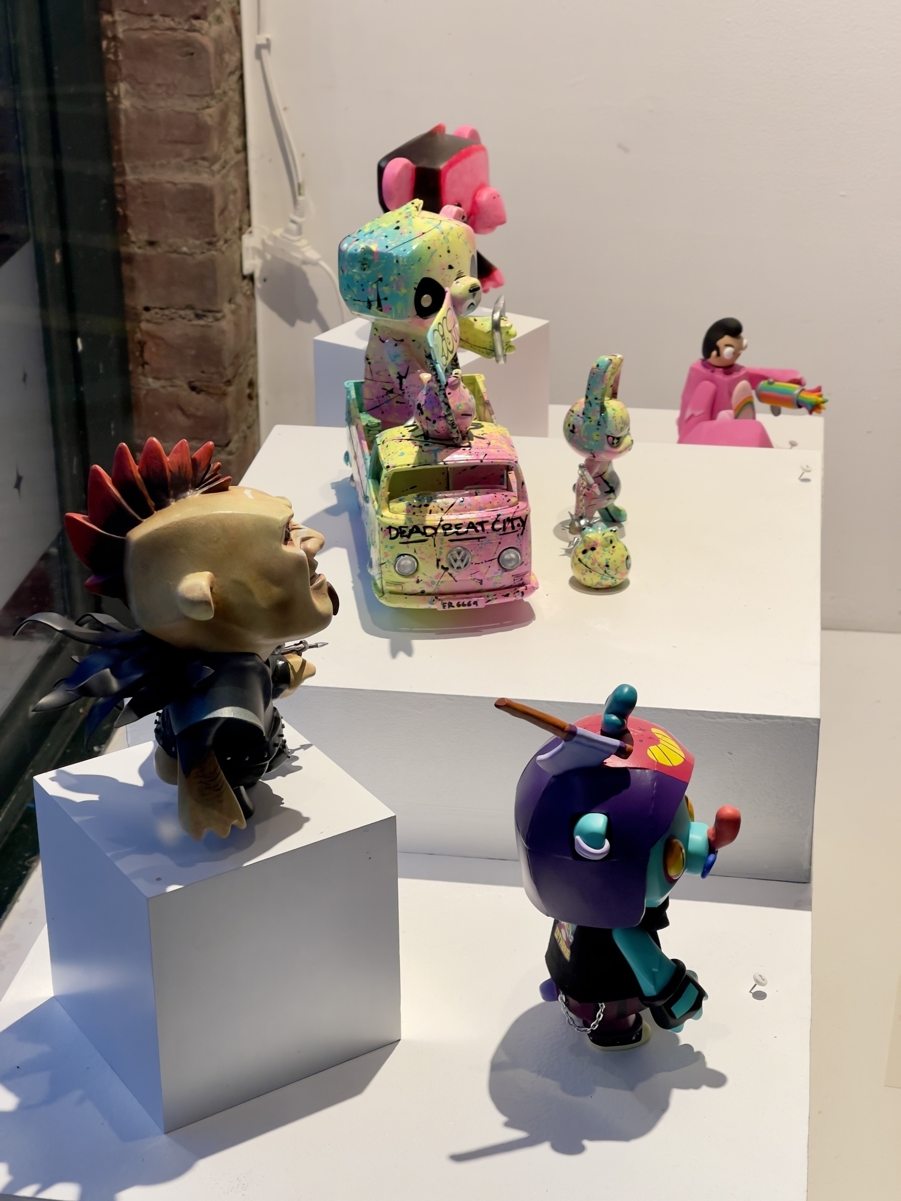 Art toy figures in a gallery window.
