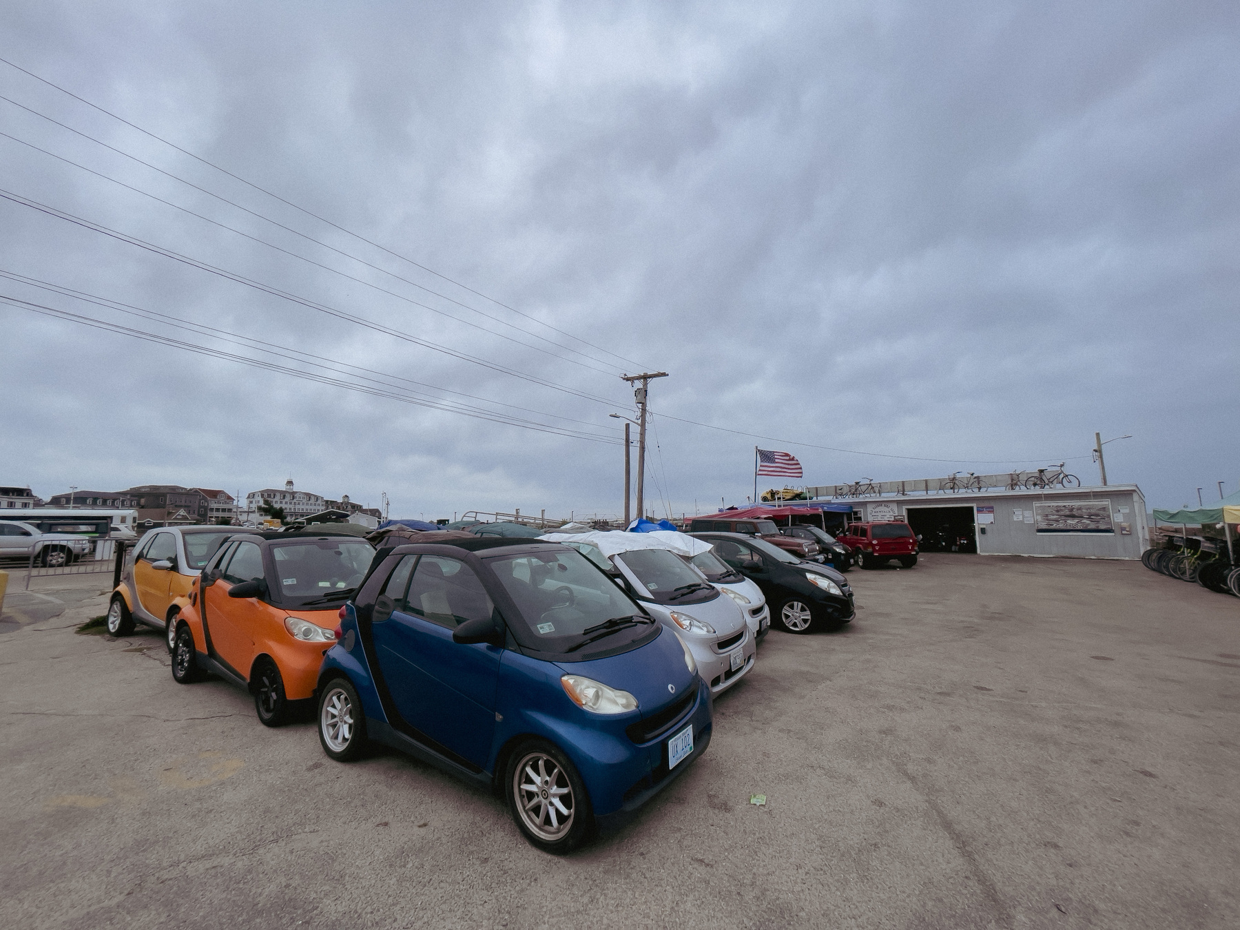 Rental cars waiting to be rented. Cloudy skies above.