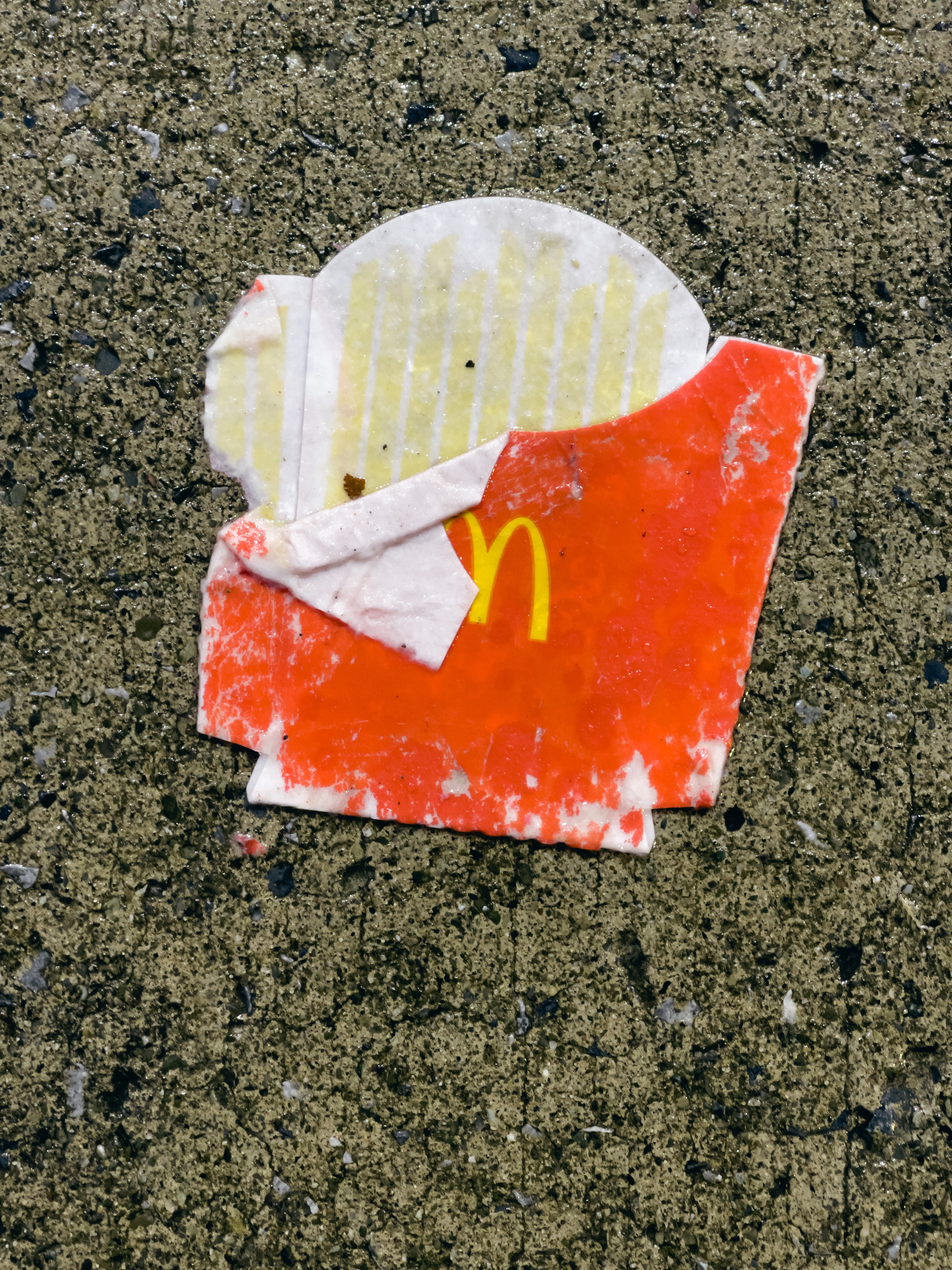 McDonald’s fries box on concrete pavement.