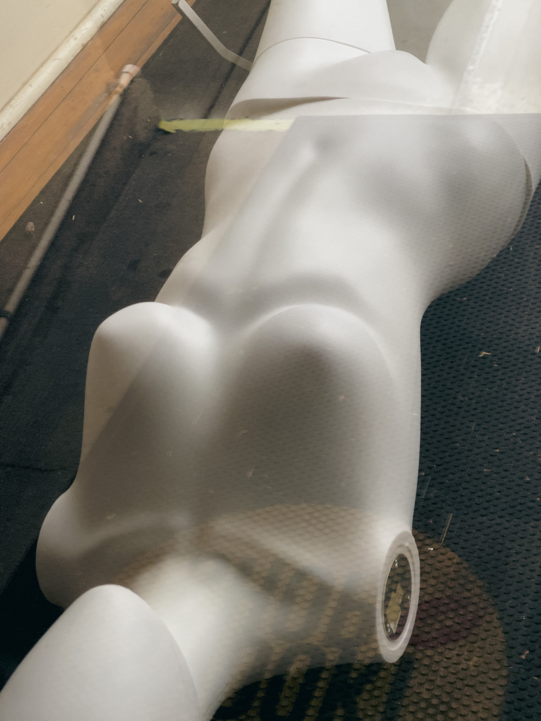 Armless female mannequin form in a shop window.