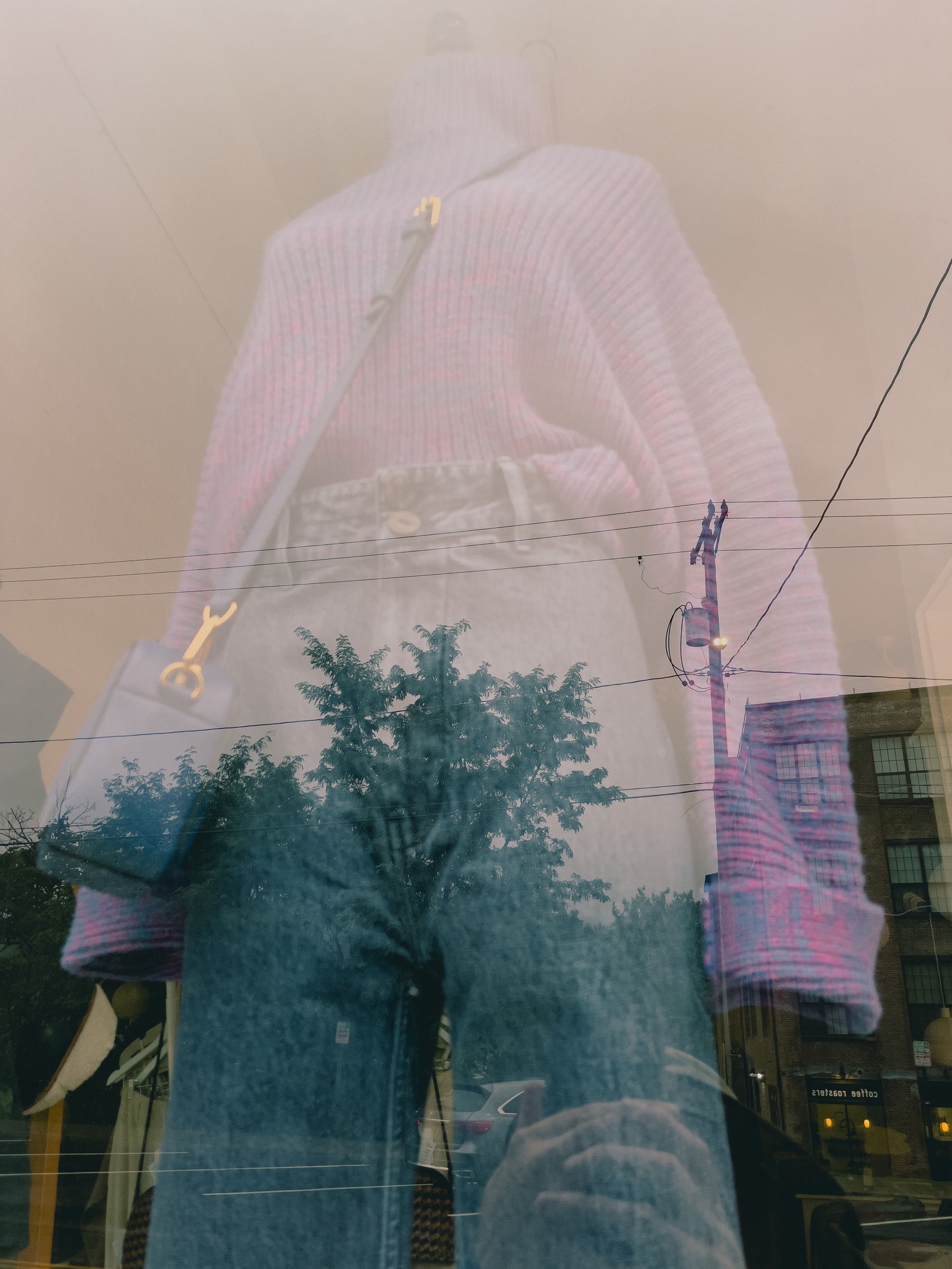 Purple/pink sweater, blue jeans, purple/pink handbag combo on mannequin in shop window. Sky, trees, building reflections layered overtop.