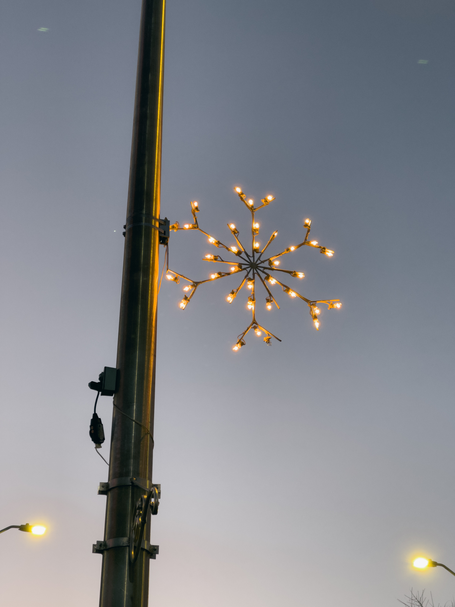 Christmas snowflake decoration lights attached to utility pole,