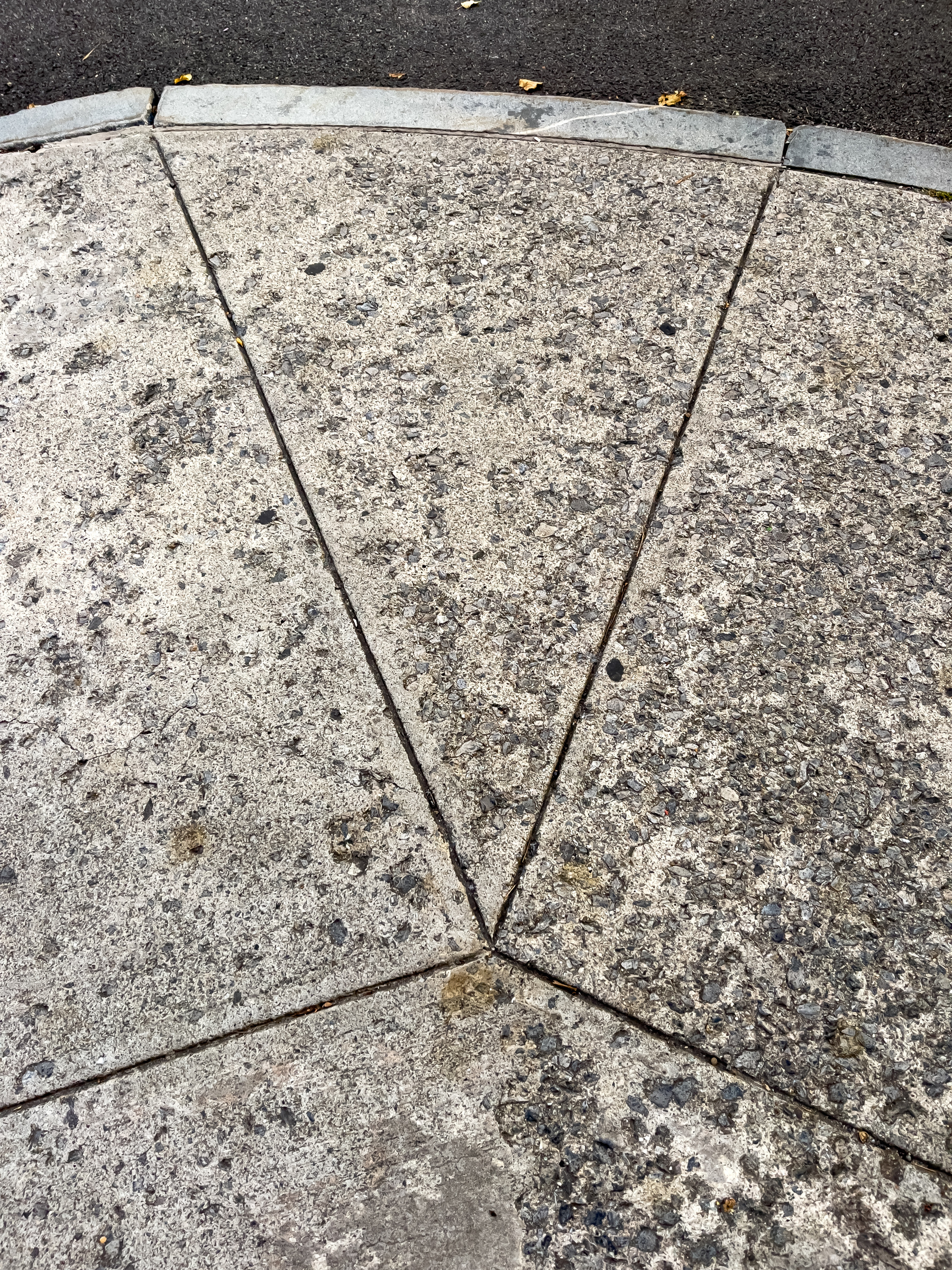 Concrete sidewalk with crack control lines forming a triangle in the middle.