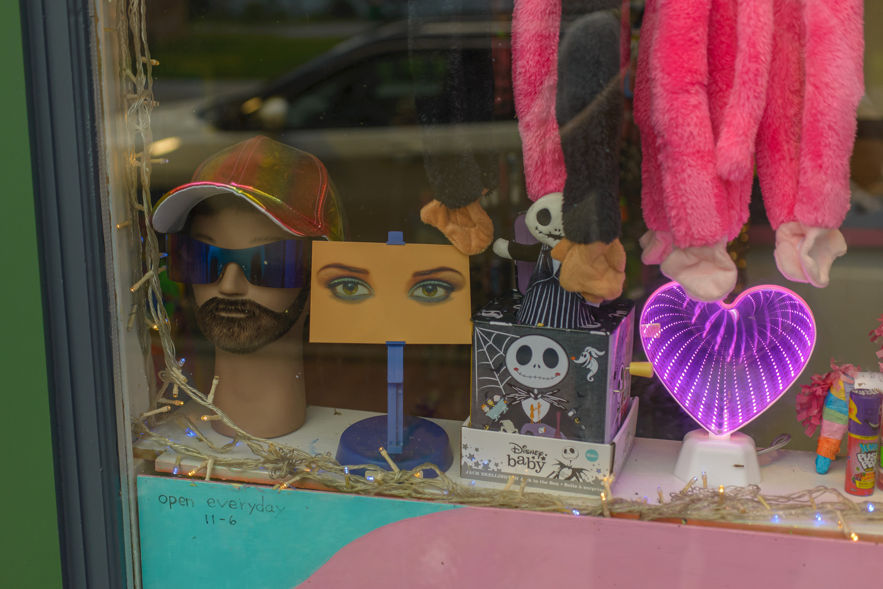 Miscellaneous items in a novelty store, including a heart wit depth of space illusion, a Jack Skellington in a box, a pair of feminine eyes, and a male head form with beard, sunglasses and gold metallic hat.