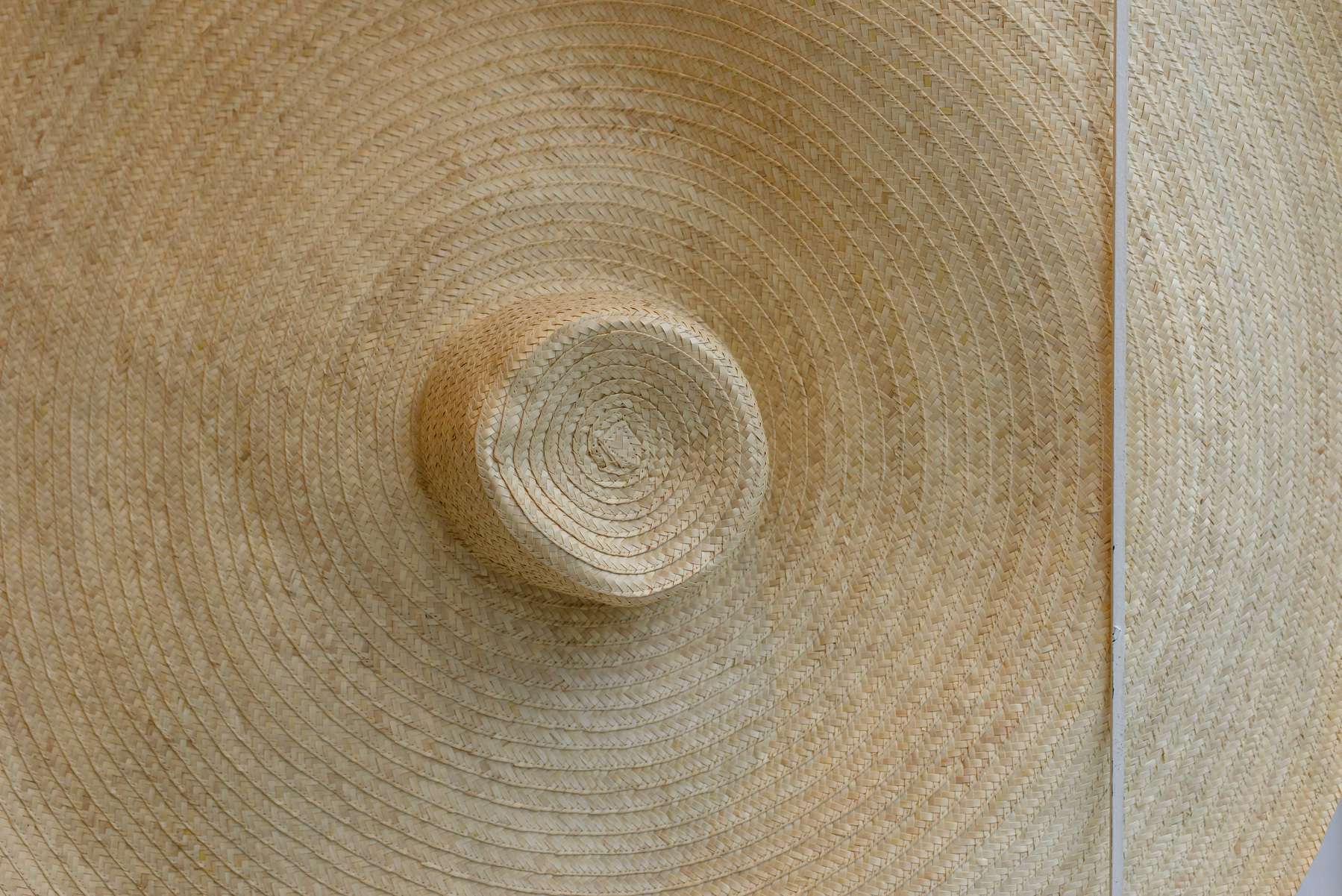 closeup of a straw hat with very wide brim, hat crown in the middle of frame, brim radiating beyond all the edges of the frame