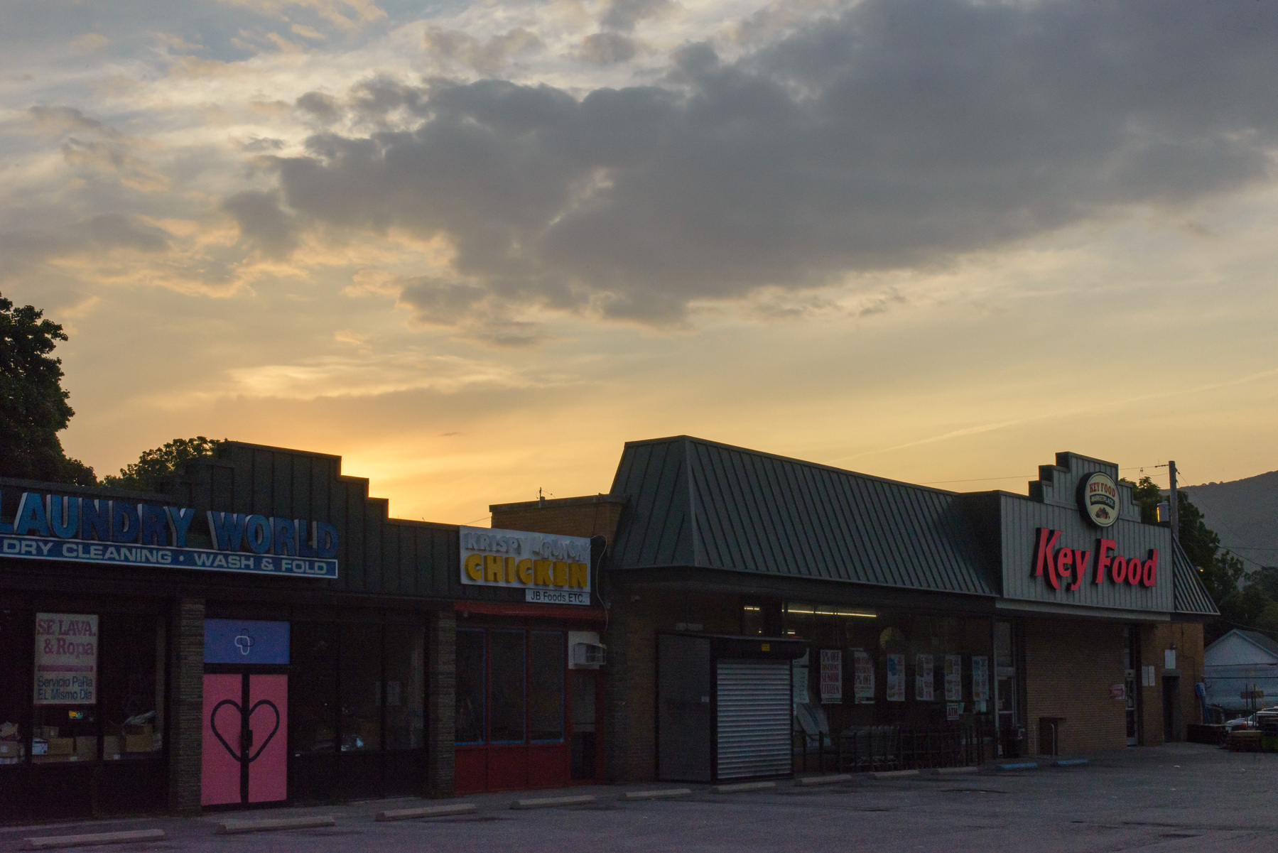 Sunrise cloudscape above a Key Food grocery store and neighboring shops.