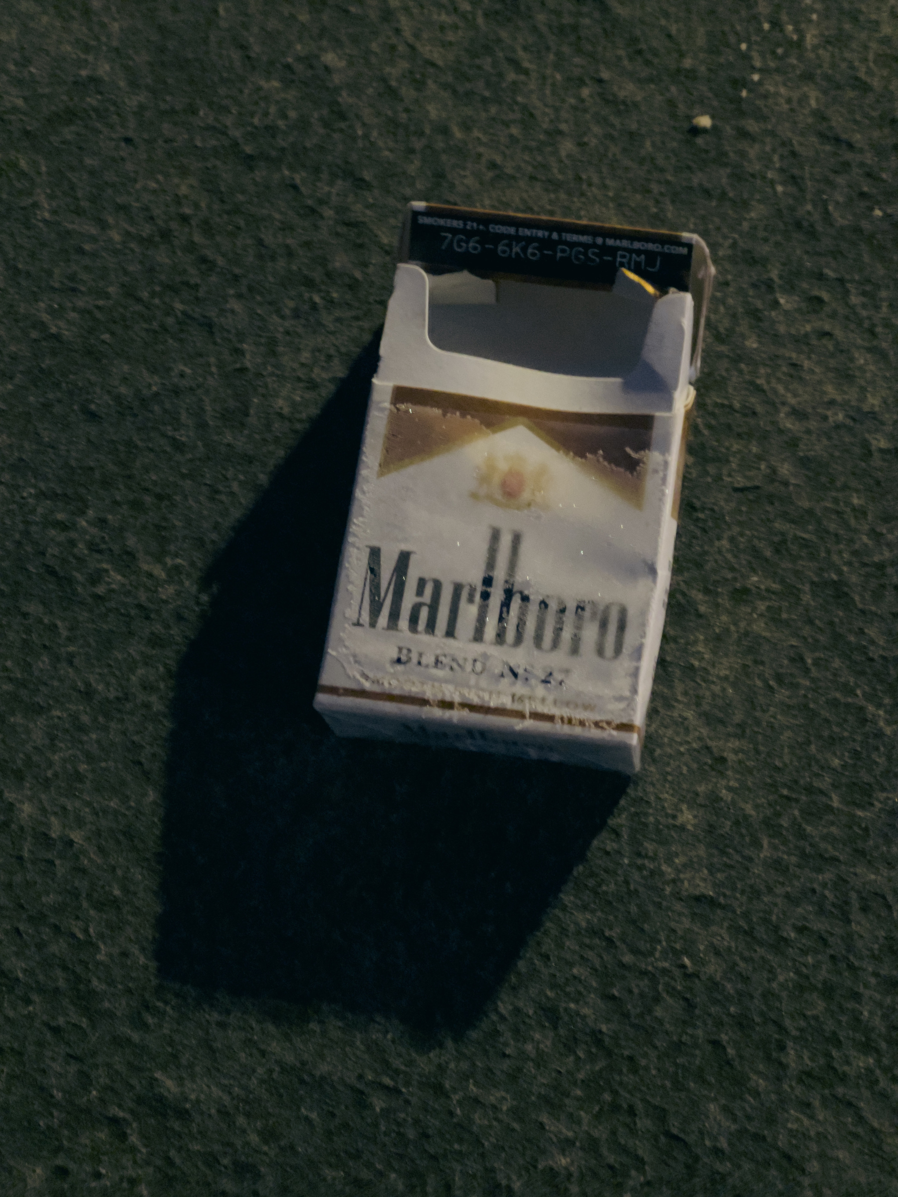 Empty Marlboro cigarette pack illuminated by streetlights.