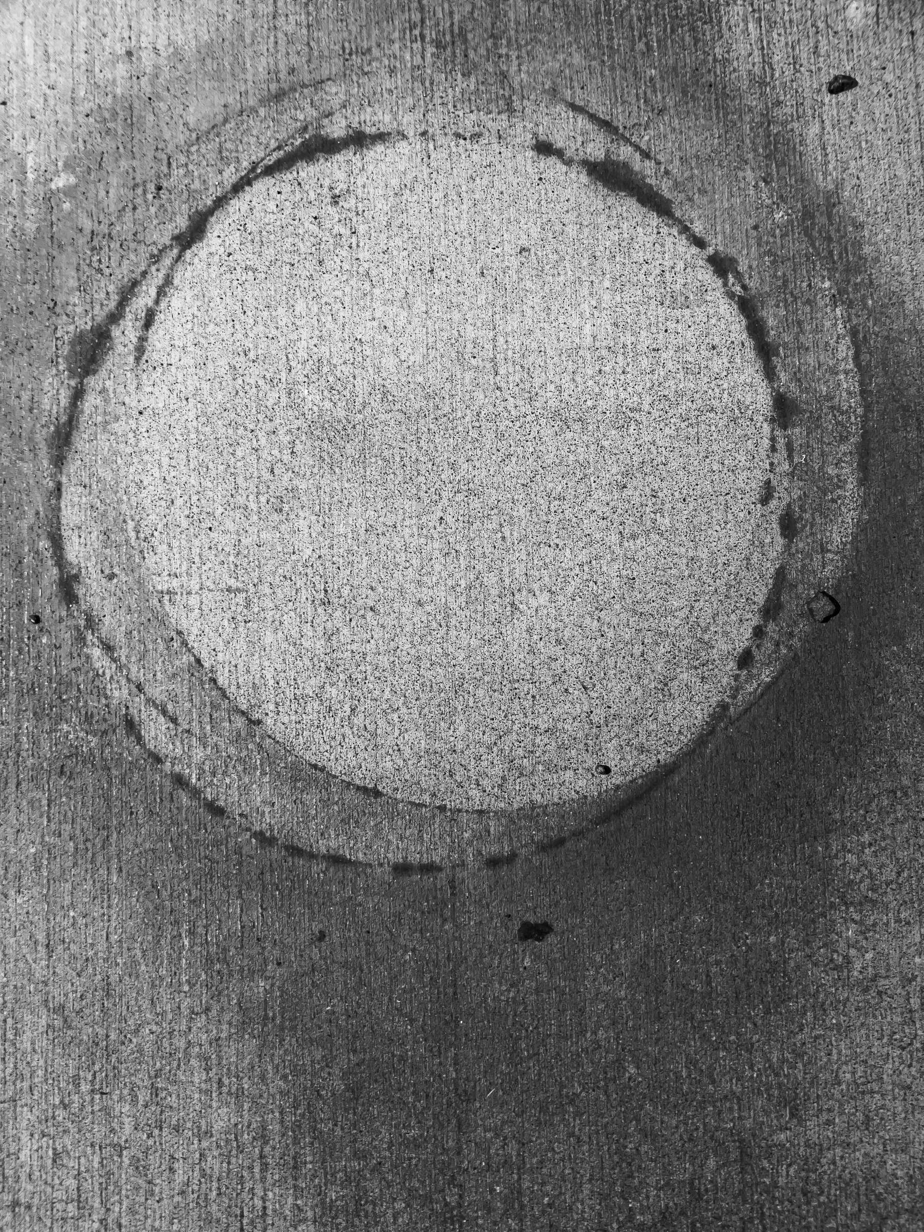 Overlapping circular stains on concrete positioned equally distant from top and sides of vertical rectangular frame. 